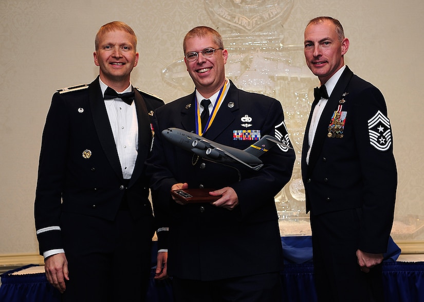 Colonel Darren Hartford, 437th Airlift Wing commander, and Chief Master Sgt. Larry Williams, 437th Airlift Wing command chief, present the 437th AW Innovator of the Year award to Master Sgt. Serge Ladd from the 437th Aerial Port Squadron during the 437th AW Annual Awards Banquet held at the Charleston Club, Jan. 18, 2013, at Joint Base Charleston - Air Base, S.C. (U.S. Air Force photo/Staff Sgt. Rasheen Douglas)
