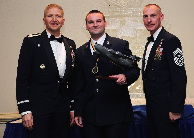 Colonel Darren Hartford, 437th Airlift Wing commander, and Chief Master Sgt. Larry Williams, 437th AW command chief, present the 437th AW Volunteer of the Year award to Airman 1st Class Zachary Cozzens from the 437th Operations Support Squadron during the 437th AW Annual Awards Banquet held at the Charleston Club, Jan. 18, 2013, at Joint Base Charleston - Air Base, S.C. (U.S. Air Force photo/Staff Sgt. Rasheen Douglas)
