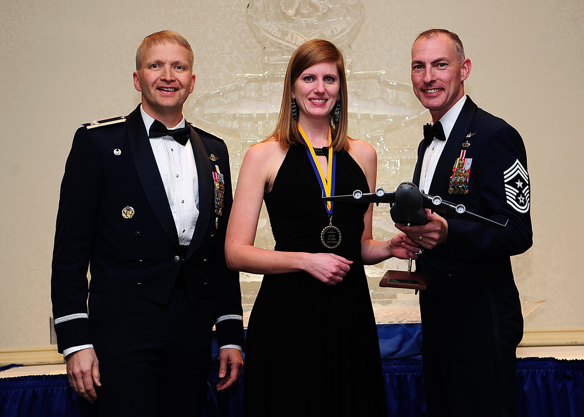 Colonel Darren Hartford, 437th Airlift Wing commander, and Chief Master Sgt. Larry Williams, 437th AW command chief, present the 437th AW Senior Grade Officer of the Year award to Rachel Boyd on behalf of her husband Capt. Adam Boyd from the 15th Airlift Squadron during the 437th AW Annual Awards Banquet held at the Charleston Club, Jan. 18, 2013, at Joint Base Charleston - Air Base, S.C. (U.S. Air Force photo/Staff Sgt. Rasheen Douglas)