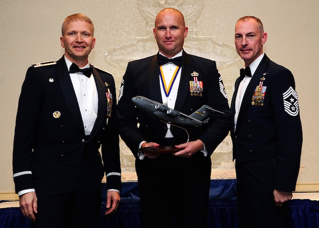 Colonel Darren Hartford, 437th Airlift Wing commander, and Chief Master Sgt. Larry Williams, 437th AW command chief, present the 437th AW Senior Noncommissioned Officer of the Year award to Senior Master Sgt. Robert Schultz from the 437th Aerial Port Squadron during the 437th AW Annual Awards Banquet held at the Charleston Club, Jan. 18, 2013, at Joint Base Charleston - Air Base, S.C. (U.S. Air Force photo/Staff Sgt. Rasheen Douglas)