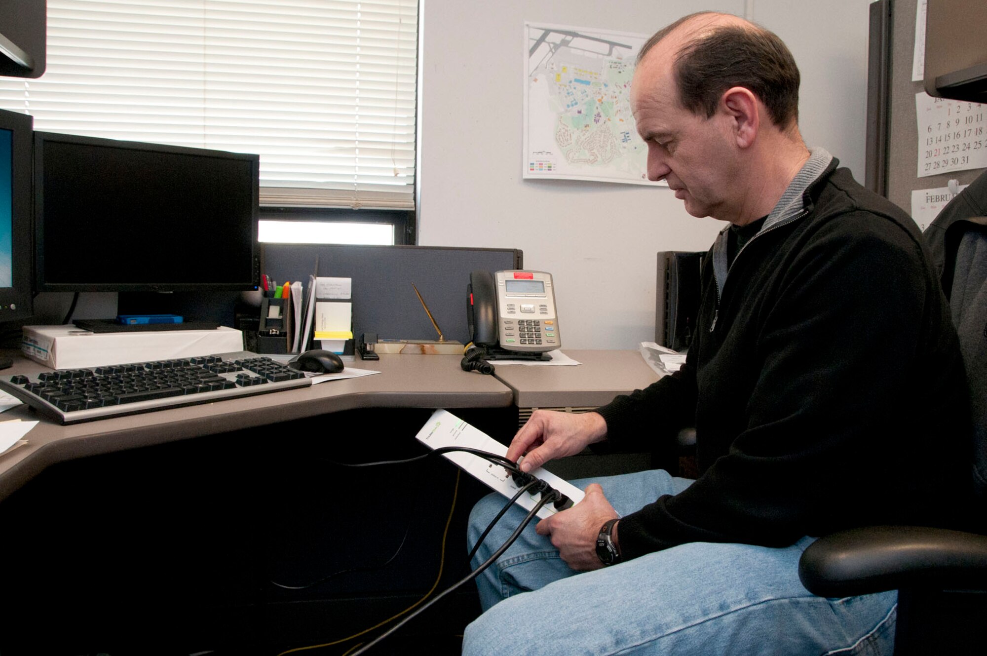 HANSCOM AIR FORCE BASE, Mass. -- Bruce Finley, Civil Engineering energy manager, plugs a computer monitor into a new Smart Power Strip that will reduce energy demand in non-active computer peripherals. Organizations on base can expect the power strips to be available for distribution soon throughout Hanscom. (U.S. Air Force photo by Mark Wyatt)