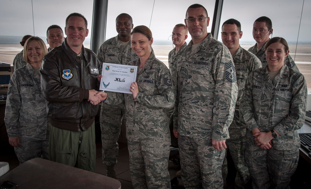 Tech Sgt. Nicole Valentine, 47th Operations Support Squadron tower watch supervisor, poses with Col. Tom Murphy, 47th Flying Training Wing commander, and Chief Master Sgt. Garry Berry, 47th FTW command chief, after being presented the XLer of the week award at Laughlin Air Force Base, Texas, Jan. 11, 2013. The XLer is a weekly award chosen by wing leadership and given to those who consistently make outstanding contributions to Laughlin and their unit. (U.S. Air Force photo/Senior Airman Nathan Maysonet)