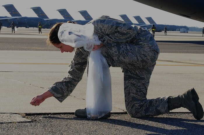 Lt.  Helen Cruz, 628th Communications Squadron cyber operations deputy flight commander  , picks up debris during the Foreign Object Debris walk   Jan. 17, 2013,  at Joint Base Charleston - Air Base, S.C. By removing FOD from runways and flightlines, Airmen help save the Air Force millions  of dollars in costly engine repairs and replacement every year.  (U.S. Air Force photo/ Airman 1st Class Chacarra Walker)