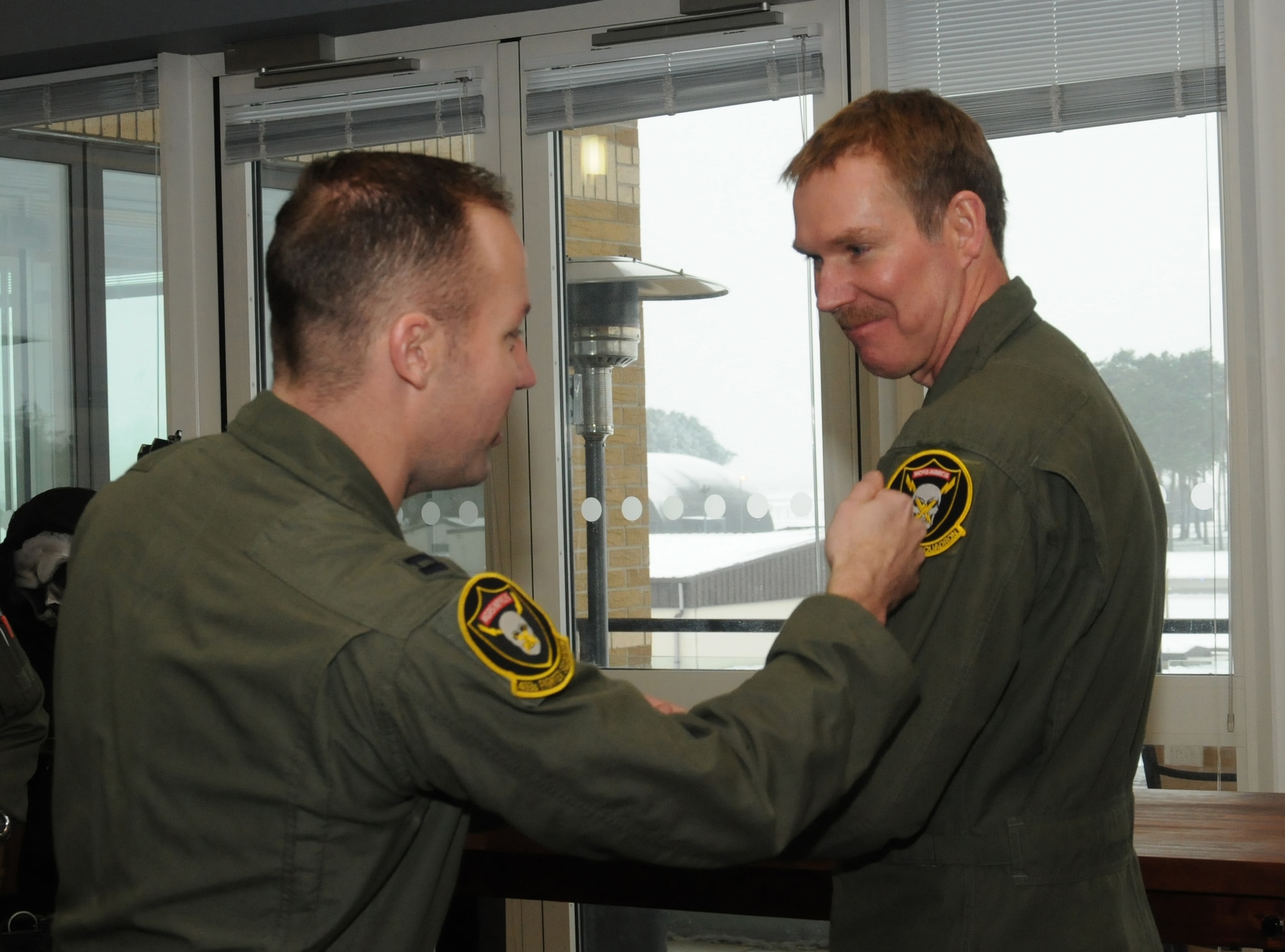 Capt. Dustin Edwards, 493rd Fighter Squadron pilot, tacks a 493rd FS unit patch on Chief Master Sgt. Christopher Powell, 100th Air Refueling Wing command chief from Cypress Fairbanks, Texas, after conducting an incentive flight Jan. 18, 2013, in an F-15 Eagle aircraft for Powell Jan. 18, 2013, at RAF Lakenheath, England. Powell earned the flight for his outstanding service over a nearly 30-year Air Force career. (U.S. Air Force photo by Tech. Sgt. Neal X. Joiner/Released)