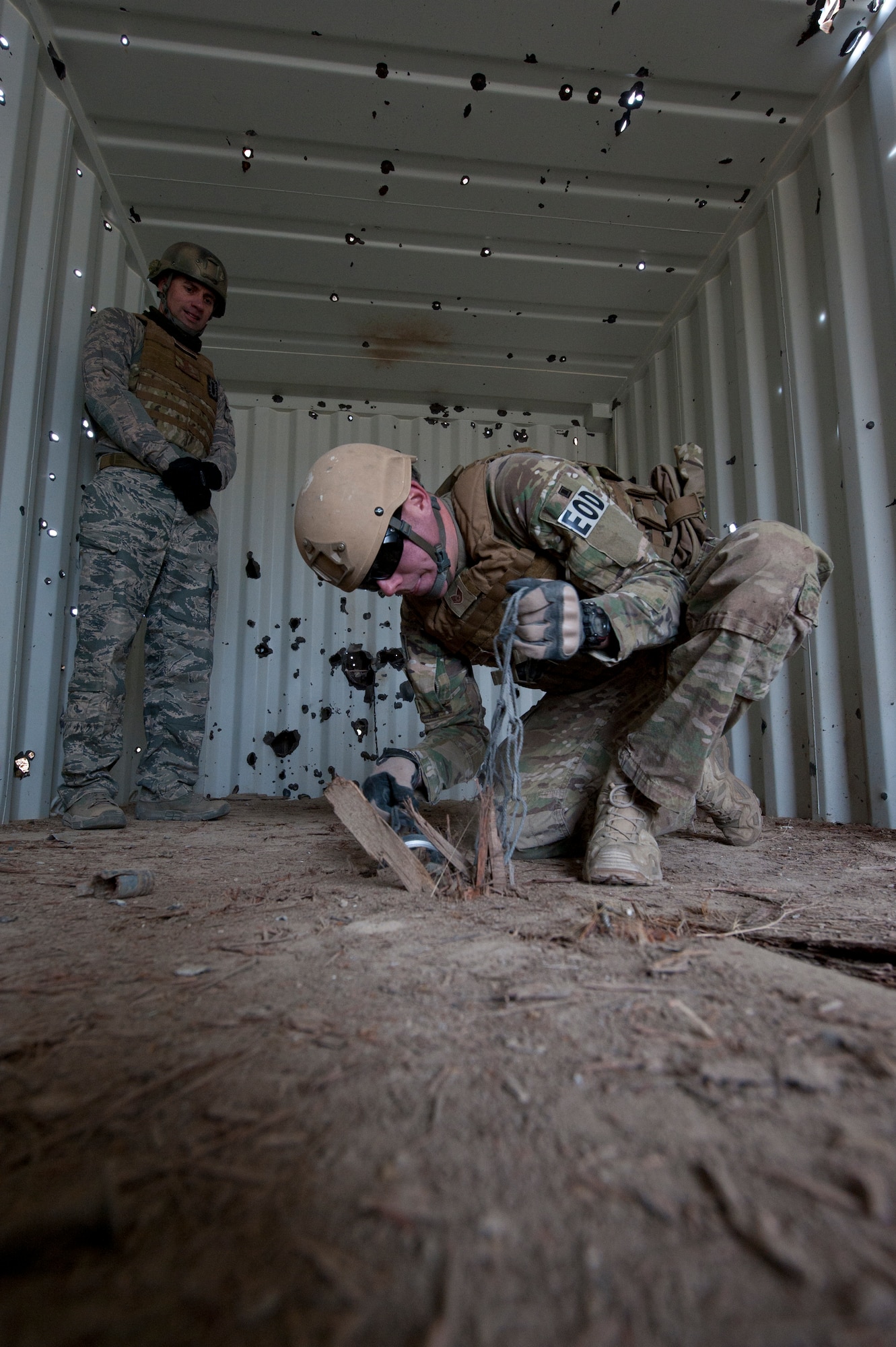 FORT CARSON, Colo. -- Staff Sgt. Jeremy Redfern, 21st Civil Engineer Squadron EOD technician, works to remove an unexploded ordnance from a building floor using a 'hook and line' kit, while supervised by Master Sgt. Paul Horton, 21st CES EOD flight chief Jan. 10 at Fort Carson.  Exercises like this are designed to expose Airmen to the physical and mental fatigue experienced while deployed. The Airmen from the 21st EOD flight use the training learned in these exercises to fulfill their role as a defensive force at home and while deployed. (U.S. Air Force photo/Staff Sgt. J. Aaron Breeden)