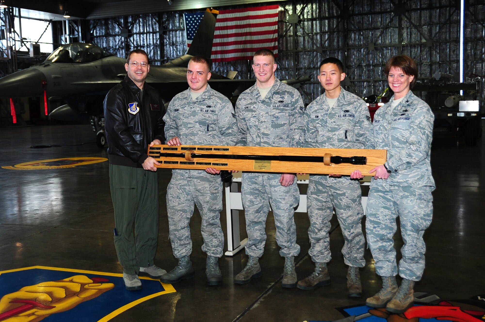 U.S. Air Force Col. Stephen Williams, 35th Fighter Wing commander, Senior Airman Ronald Olney, Airman 1st Class Michael Howell, 13th Aircraft Maintenance Unit weapons load crew members, Senior Airman Stephen Kim, 13th Aircraft Maintenance Unit weapons load crew team chief, and Col. Cheryl Minto, 35th Maintenance Group commander, gather together as the team receives the award for best load crew of the quarter.  This is the second consecutive win for the 13th Aircraft Maintenance Unit weapons load crew team. (U.S. Air Force photo by Staff Sgt. April Quintanilla)