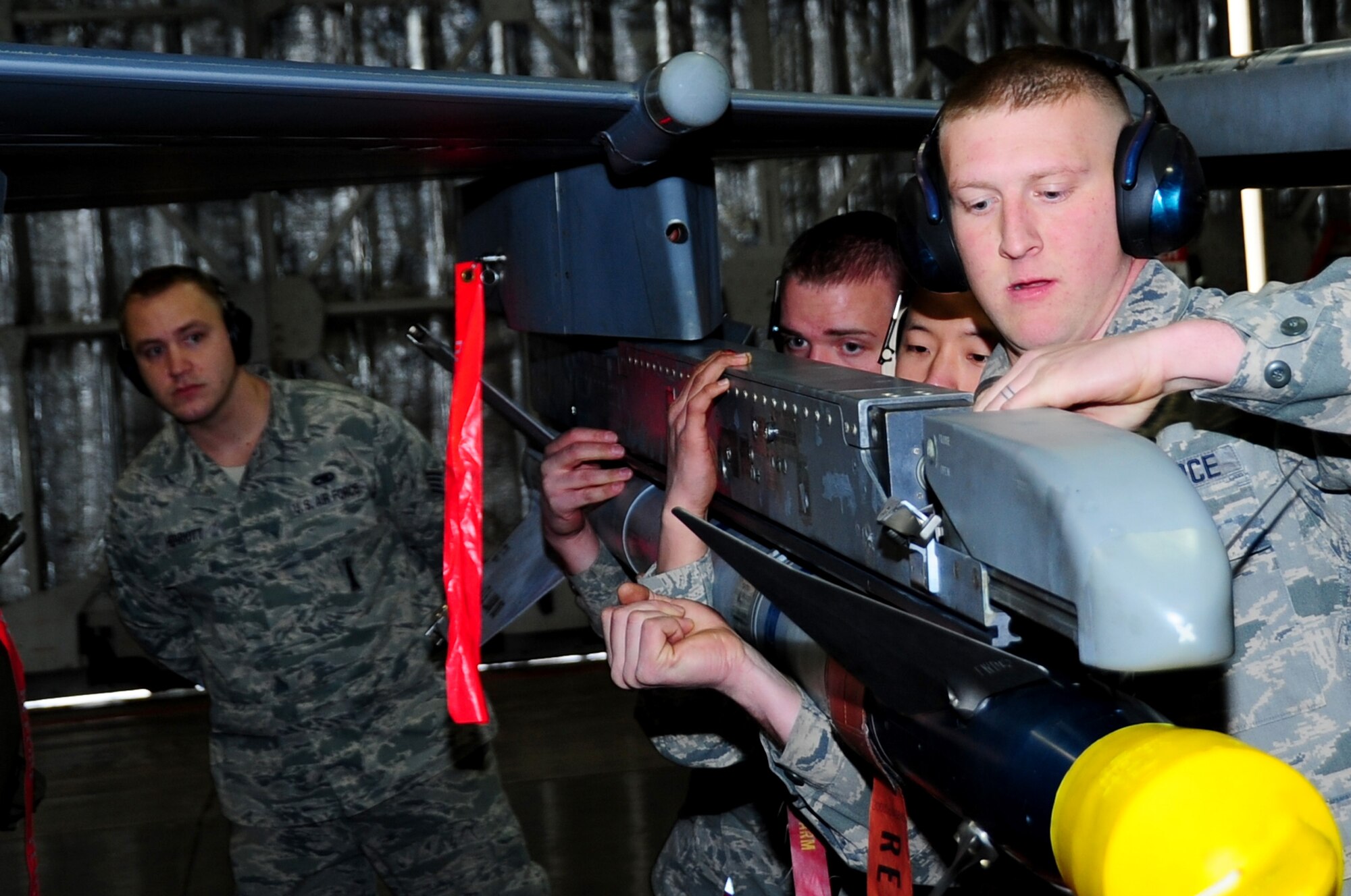 U.S. Air Force Staff Sgt. Kevin Herriott (back), 35th Maintenance Group weapons standardization, evaluates as Airman 1st Class Michael Howell (front), Senior Airmen Stephen Kim (center) and Ronald Olney, 13th Aircraft Maintenance Unit weapons load crew members, load an AIM-9L/M on an F-16 Fighting Falcon during a Load Crew of the Quarter Competition at Misawa Air Base, Japan, Jan. 18, 2013.  This competition grades 13th and 14th Fighter Squadron AMU members on a variety of areas which include safety, appearance, speed and accuracy.  (U.S. Air Force photo by Staff Sgt. April Quintanilla)