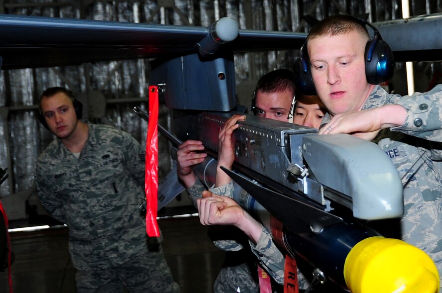 U.S. Air Force Staff Sgt. Kevin Herriott (back), 35th Maintenance Group weapons standardization, evaluates as Airman 1st Class Michael Howell (front), Senior Airmen Stephen Kim (center) and Ronald Olney, 13th Aircraft Maintenance Unit weapons load crew members, load an AIM-9L/M on an F-16 Fighting Falcon during a Load Crew of the Quarter Competition at Misawa Air Base, Japan, Jan. 18, 2013.  This competition grades 13th and 14th Fighter Squadron AMU members on a variety of areas which include safety, appearance, speed and accuracy.  (U.S. Air Force photo by Staff Sgt. April Quintanilla)