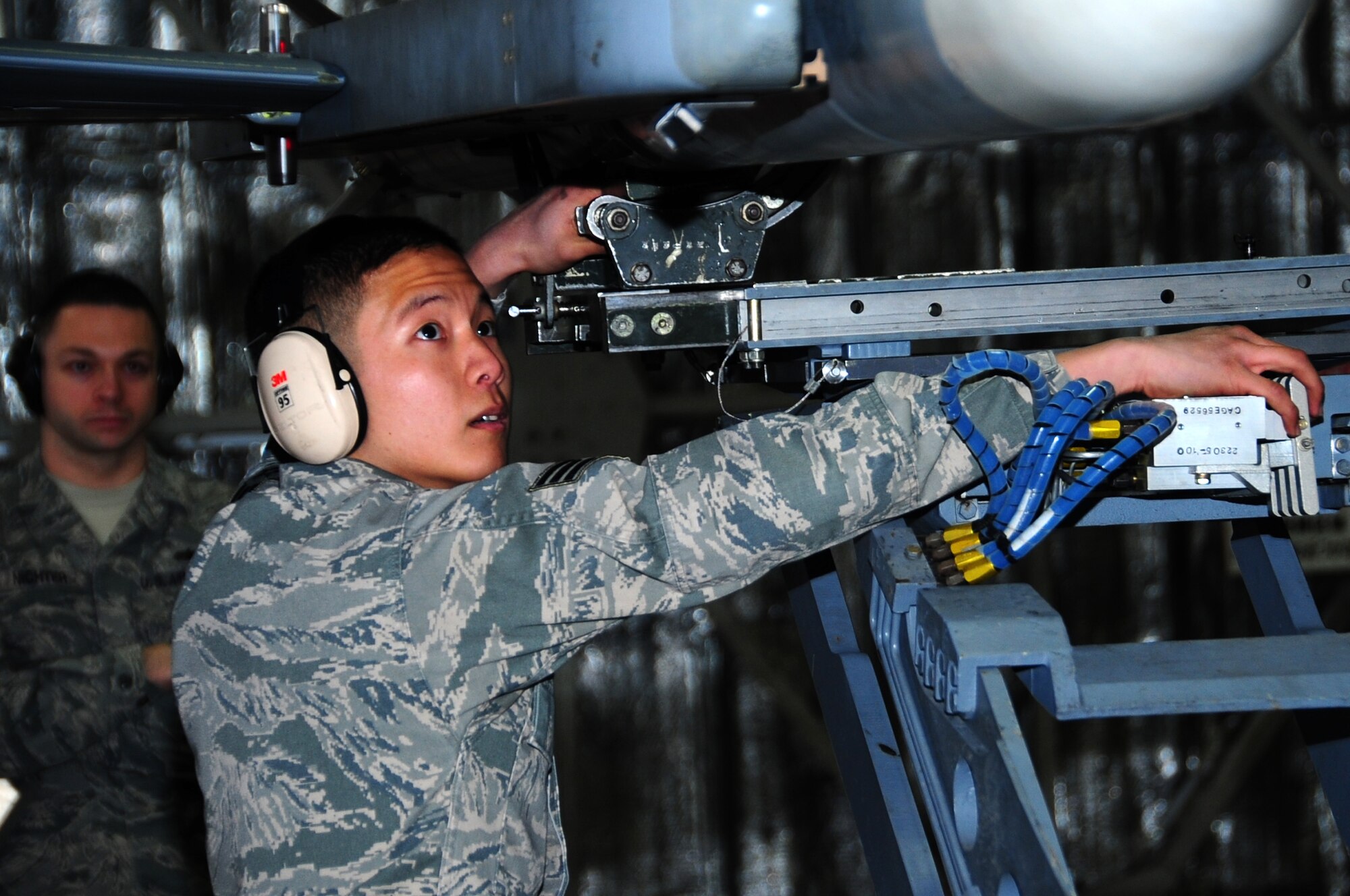 U.S. Air Force Senior Airman Stephen Kim, 13th Fighter Squadron weapons load crew member, secures a AIM-120 Advanced Medium-Range Air-to-Air Missile as Staff Sgt. Michael Nichter, 35th Maintenance Group weapons standardization, evaluates during the first Load Crew of the Quarter Competition of the 2013 calendar year at Misawa Air Base, Japan, Jan. 18, 2013.  The inspectors look over the final product for any discrepancies that may deduct points from the winning team.  (U.S. Air Force photo by Staff Sgt. April Quintanilla)