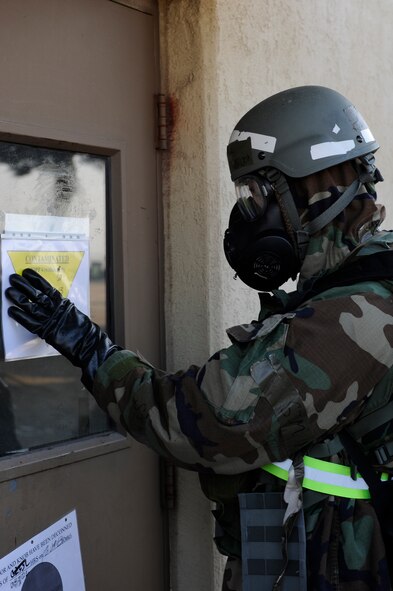Senior Airman Justin Holbrook, 8th Operations Support Squadron, places a contamination sign on his building during exercise Beverly Midnight 13-1 at Kunsan Air Base, Republic of Korea, Jan. 18, 2013. After the post-attack reconnaissance   sweep, the team determined their building was hit by a chemical attack. (U.S. Air Force photo by Senior Airman Marcus Morris/Released)  