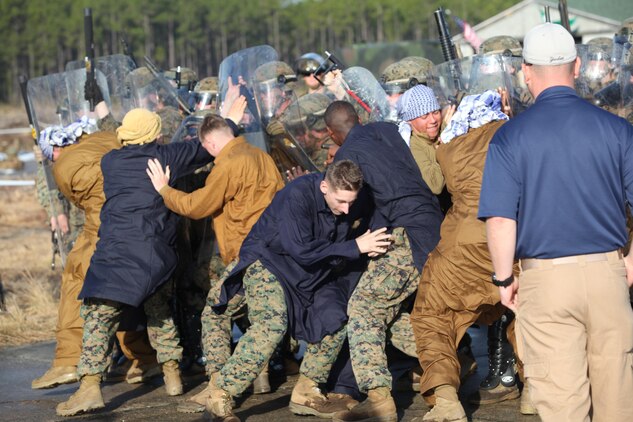 Marines with Easy Company, 2nd Battalion, 2nd Marine Regiment, hold back Marine role players that are attacking the mock embassy as an evaluator watches and grades them. Marines and sailors with Easy Company, and the 2013 iteration of the Black Sea Rotational Force conducted their first embassy reinforcement mission rehearsal exercise the week of January 7.