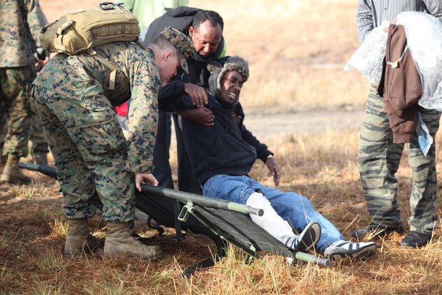 Petty Officer 3rd Class Andrew Sanders, a hospital corpsman with the Black Sea Rotational Force13 and an Elizabeth City, N.C., native, helps a role player, who has a mock injury, onto a stretcher going to the medical aid station. Marines and sailors with the 2013 iteration of BSRF conducted their first noncombatant evacuation mission rehearsal exercise the week of January 7. 