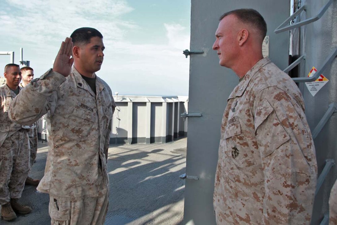 Sgt. Jacob M. Johnson (left), imagery analyst, Command Element, 15th Marine Expeditionary Unit, re-enlists under the authority of Col. Scott D. Campbell, the unitâ€™s commanding officer, while aboard the USS Peleliu, Jan. 14. The 15th MEU is deployed as part of the Peleliu Amphibious Ready Group as a U.S. Central Command theater reserve force, providing support for maritime security operations and theater security cooperation efforts in the U.S. 5th Fleet area of responsibility. Johnson, 28, is from Whittier, Calif. (U.S. Marine Corps photo by Cpl. John Robbart III)