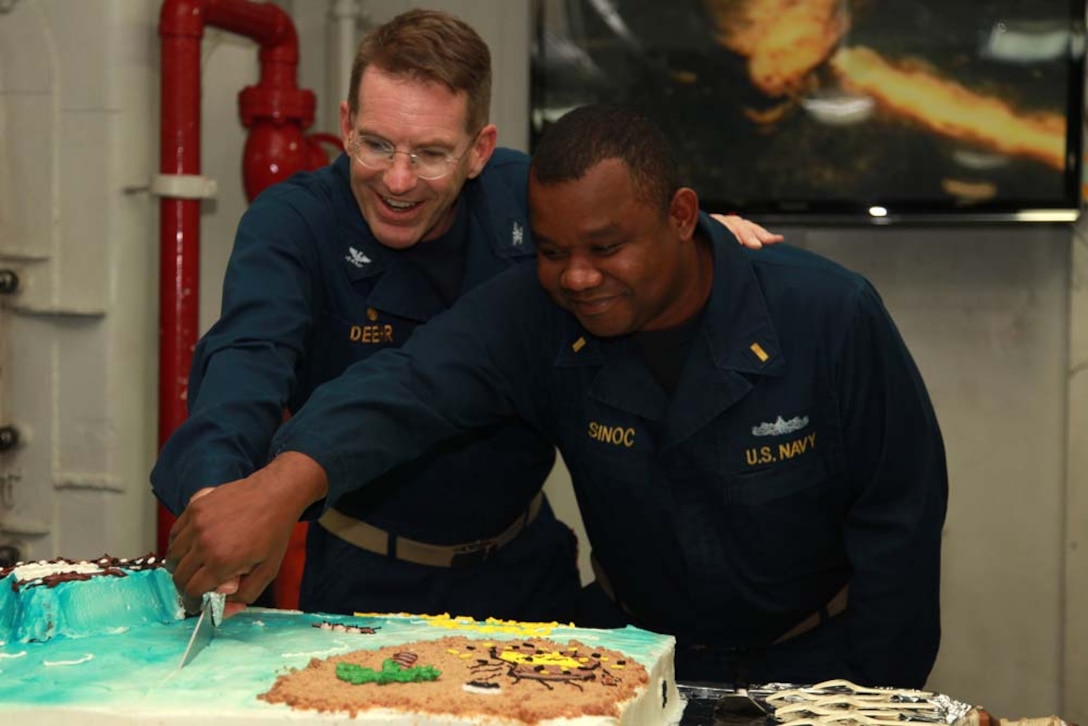 Navy Capt. John Deehr, commanding officer, USS Peleliu, and Ensign Brandley Sinoc, shipâ€™s bosâ€™n, cut a cake to commemorate the half-way point of the 15th MEU and Peleliu Amphibious Ready Group deployment, Jan. 17. To celebrate the event, the shipâ€™s food services division made a special meal for the embarked service members that included steak, king crab legs and cake. The 15th MEU is deployed as part of the Peleliu ARG as a U.S. Central Command theater reserve force, providing support for maritime security operations and theater security cooperation efforts in the U.S. 5th Fleet area of responsibility. (U.S. Marine Corps photo by Cpl. John Robbart III)