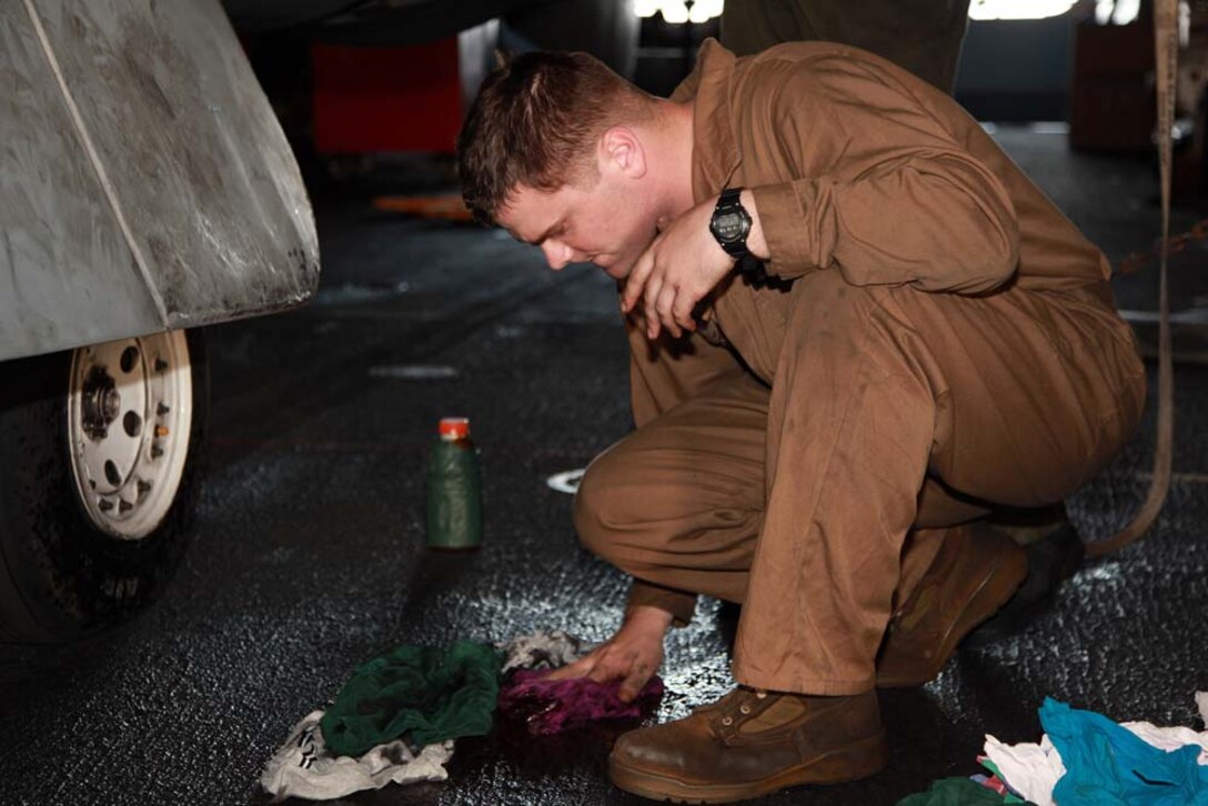 Corporal Cody A. Olson, AV-8B airframes mechanic, Marine Medium Helicopter Squadron 364 (Rein.), 15th Marine Expeditionary Unit, cleans up a hydraulic fluid spill from an AV-8B Harrier in the hangar bay of the USS Peleliu, Jan. 18. The 15th MEU is deployed as part of the Peleliu Amphibious Ready Group as a U.S. Central Command theater reserve force, providing support for maritime security operations and theater security cooperation efforts in the U.S. 5th Fleet area of responsibility. Olson, 22, is from White Lake, Wis. (U.S. Marine Corps photo by Cpl. John Robbart III)