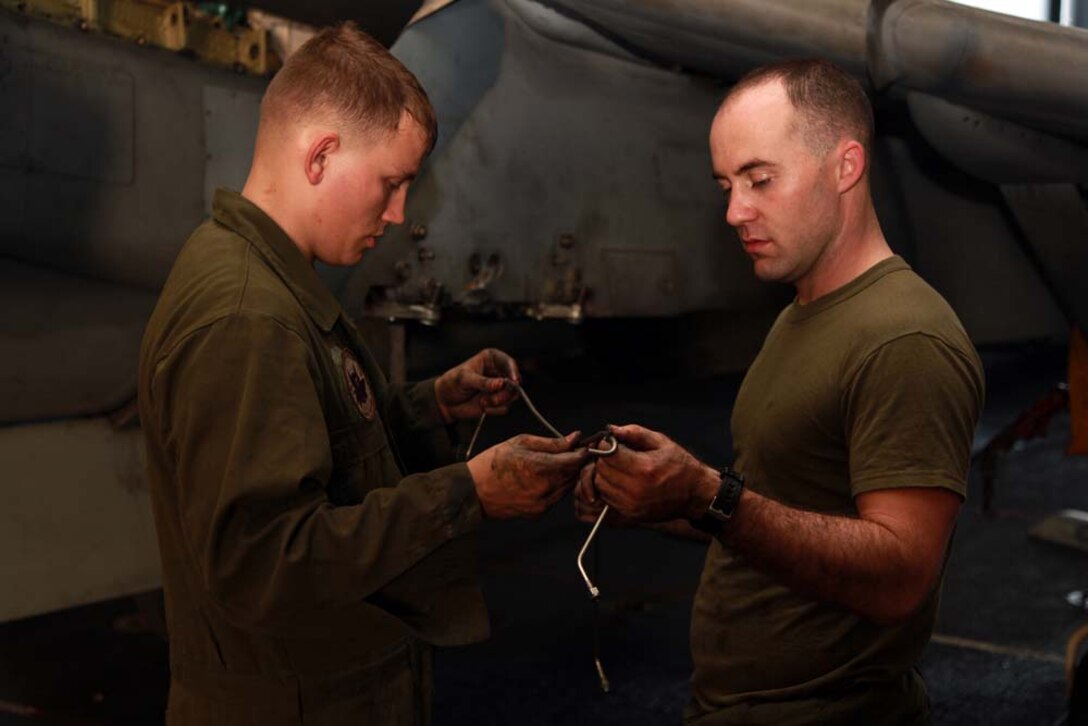 Corporal Dustin W. Cawley (right), and Lance Cpl. Jesse S. Hager, both AV-8B airframes mechanics with Marine Medium Helicopter Squadron 364 (Rein.), 15th Marine Expeditionary Unit, analyze a fluid pipe from an AV-8B Harrier in the hangar bay of the USS Peleliu, Jan. 18. The 15th MEU is deployed as part of the Peleliu Amphibious Ready Group as a U.S. Central Command theater reserve force, providing support for maritime security operations and theater security cooperation efforts in the U.S. 5th Fleet area of responsibility. Cawley, 25, is from Folkston, Ga., and Hager, 23, is from Ionia, Mich. (U.S. Marine Corps photo by Cpl. John Robbart III)