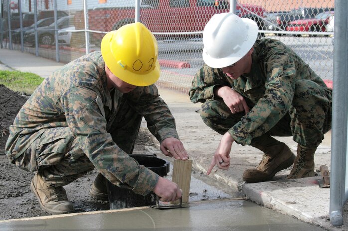 Lance Cpl. Bradley Bachman, left, and Cpl. Kenneth Storvick, both combat engineers with Marine Wing Support Squadron 271, smooth freshly-laid concrete outside the Marine Attack Squadron 223 hangar here Jan. 9.