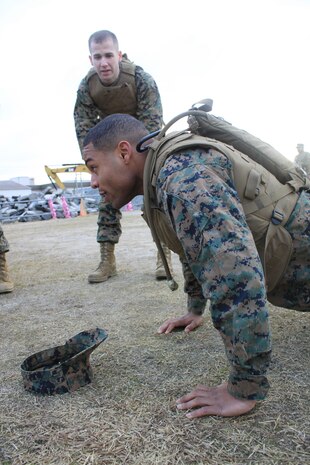 Lance Cpl. Justin Coverdale, Ironman Team Competition participant, cheers on Lance Cpl. Ronald Watts, Ironman Team Competition Participant, during the Ironman Team Competition, which started at the obstacle course here, Jan. 18, 2013.