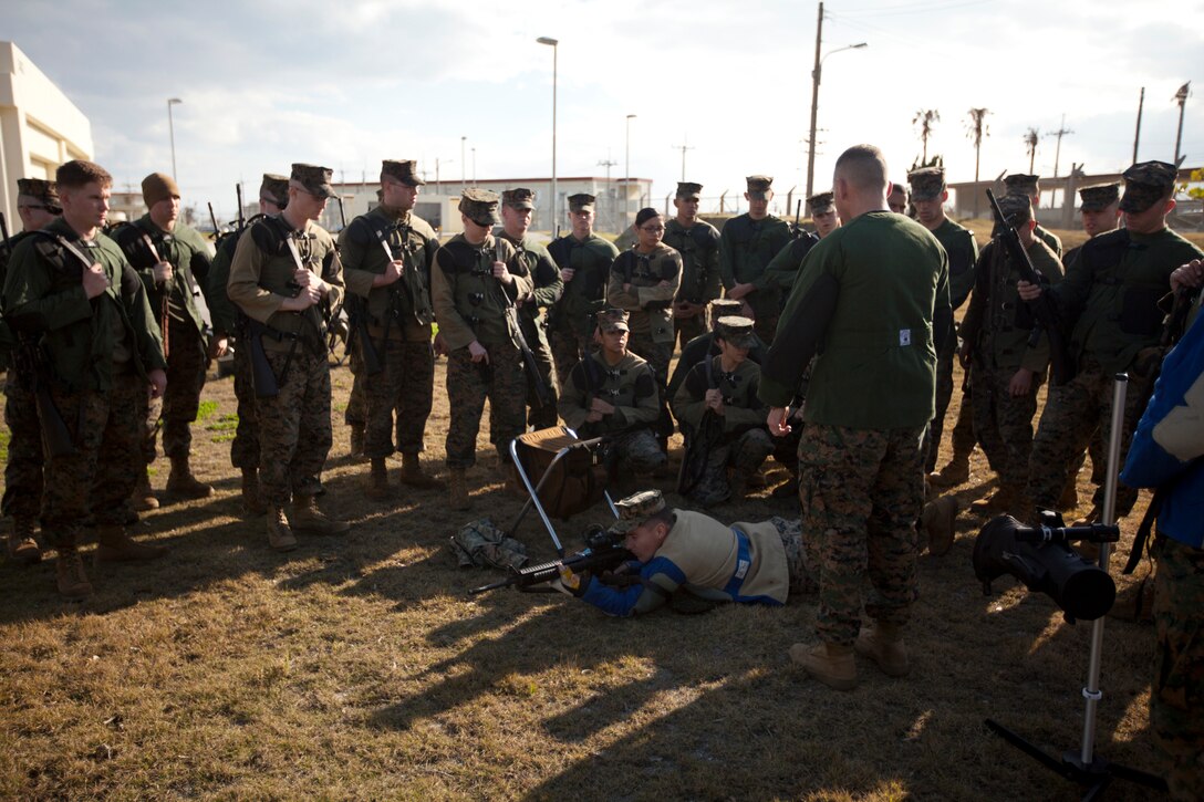 Gunnery Sgt. Larry J. Arnold shows Marines from the Marine Corps Base Butler team the proper prone position Jan. 18 during the first stages of the Far East Division Matches at Camp Schwab. During the matches, Marines with various III Marine Expeditionary Force units will compete using the M16A2 service rifle and M9 service pistol. Arnold is the coach for the MCB Butler team.