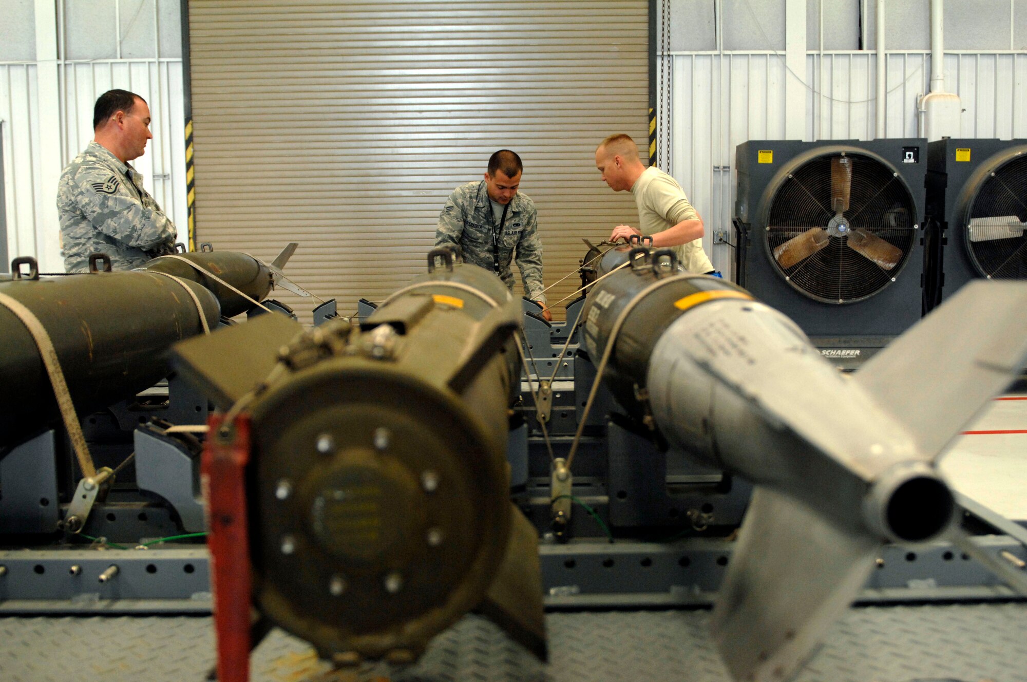U.S. Air Force Senior Airman Adam D'Eredita and Staff Sgt. Bryan Kessler, 355th Aircraft Maintenance Squadron, prepare a 500-pound bomb for loading during a practice run on Davis-Monthan Air Force Base, Ariz., Jan. 23, 2012. Instructors from the 355th Maintenance Operations Squadron observed as the three-man team successfully loaded 500-pound bombs onto an aircraft. (U.S. Air Force photo by Senior Airman Saphfire Cook)