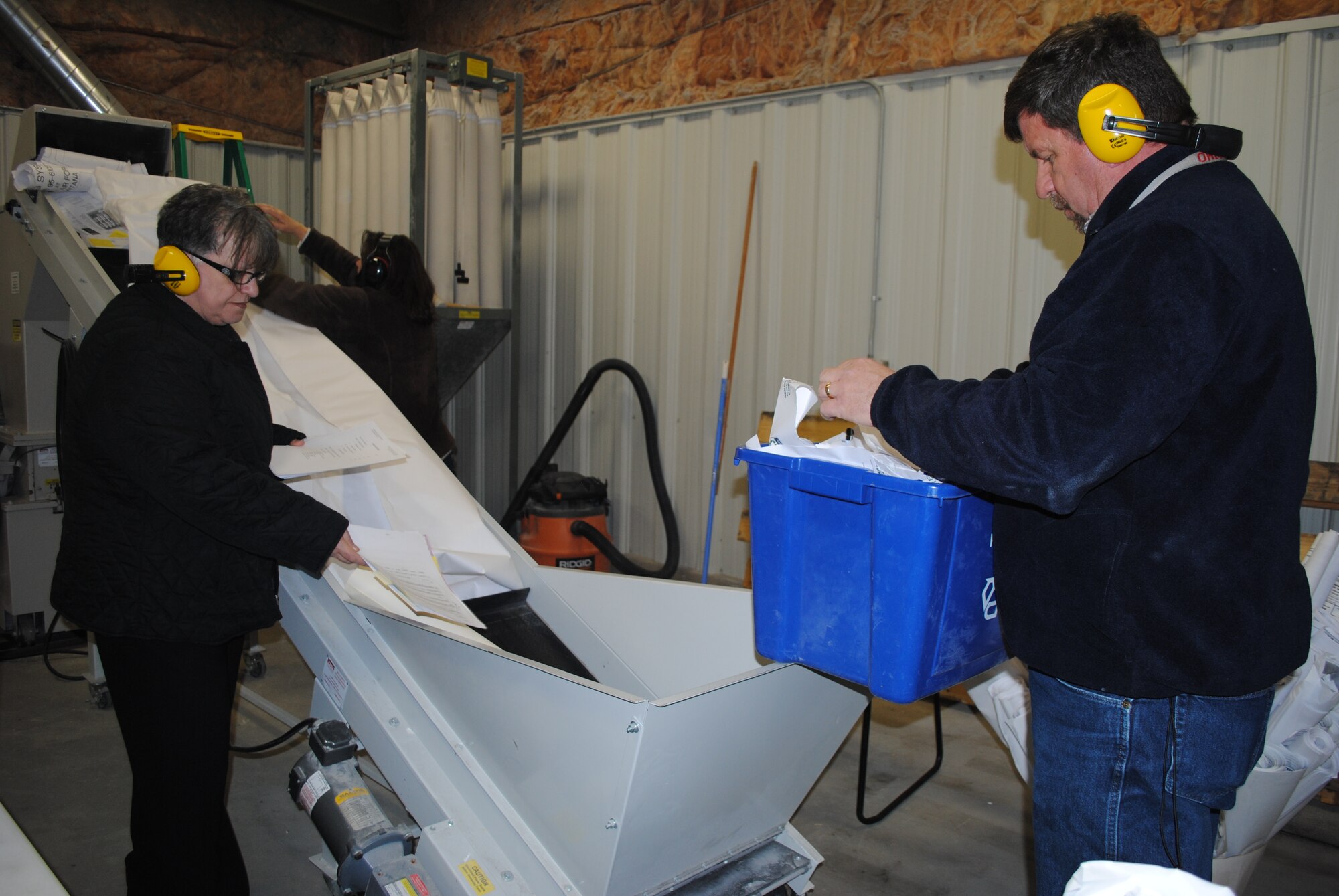 Bianca Bowen, 341st Missile Wing personnel security chief, left, Joanne Bratten, 341st MW information security chief, background, and Michael Ward, 341st MW information protection chief, destroy various unit’s controlled unclassified materials on the industrial disintegrator in Bldg. 411 during a base-wide clean-out day. Units and squadrons interested in scheduling an appointment to shred classified and unclassified items at the shredder are required to take the shredder training and can do this by calling Eileen Gallagher at 731-2266. (U.S. Air Force photo/Airman 1st Class Katrina Heikkinen)
