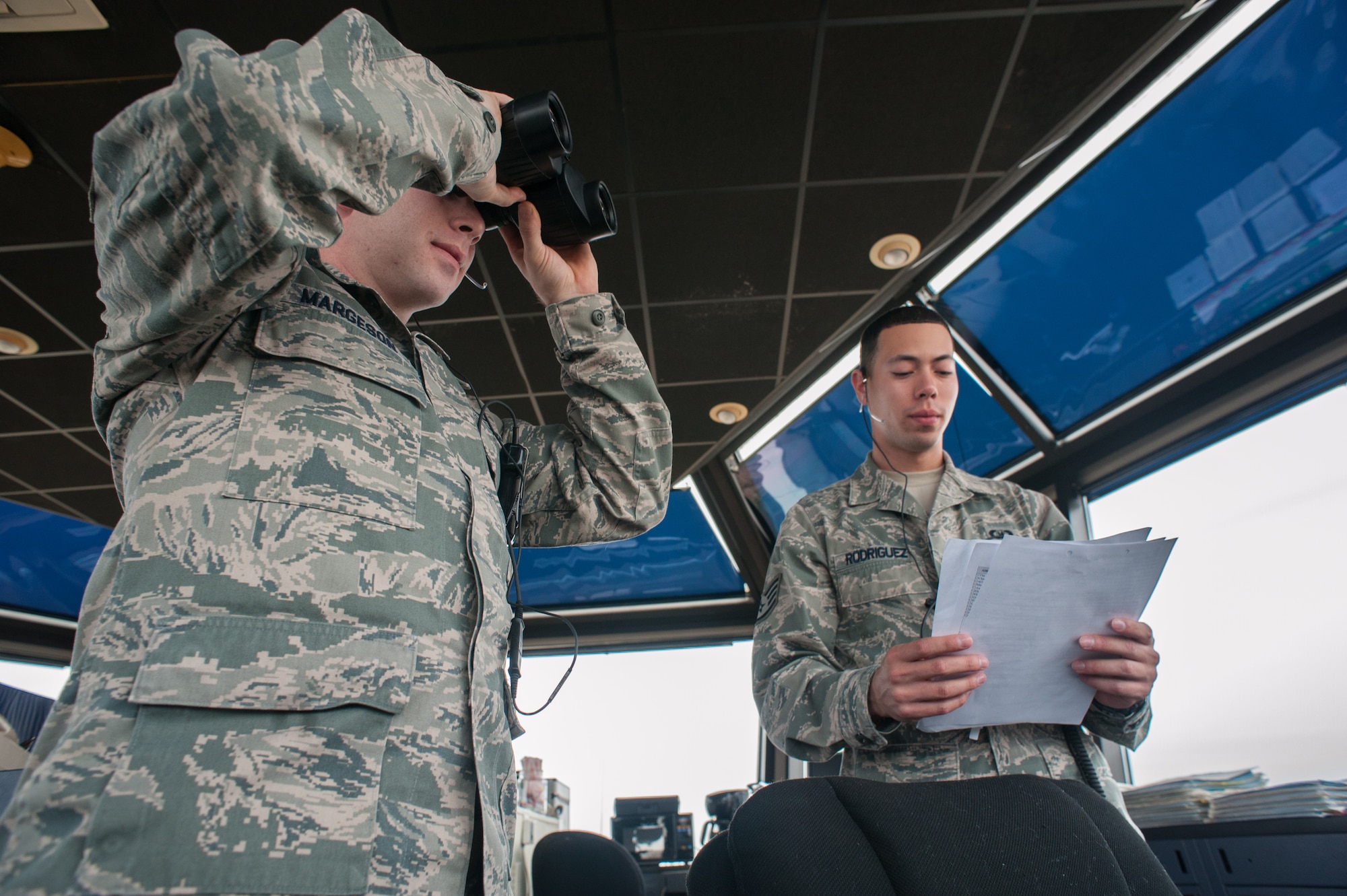 Staff Sgt. Kyle Margeson, air traffic controller watch supervisor, and Staff Sgt. Jose Rodriguez, air traffic controller apprentice, both of the 305th Operations Support Squadron, scan the runway for birds and debris to maintain situational awareness Jan. 11, 2013, at the air traffic control tower. The OSS provides the safe flow of arrivals and departures 24/7 to Joint Base McGuire-Dix-Lakehurst, N.J. Margeson hails from Carlisle, Pa., and Rodriguez hails from Philadelphia. (U.S. Air Force photo by Russ Meseroll/Released)