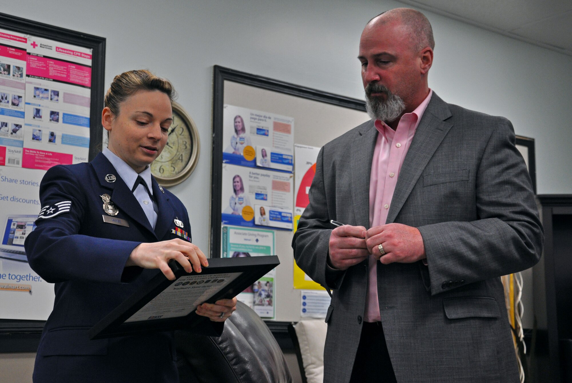Staff Sgt. Stefanie McKee prepares to hand over a Statement of Support for the Guard and Reserve Jan. 23 to an emotional John Peasley, manager of the Wal-Mart in Yelm, Wash. McKee nominated Peasley for an Employee Support of the Guard and Reserve Patriot Award for his support of the 57 Reservists he has employed there. (U.S. Air Force Photo/Airman 1st Class Madelyn McCullough)