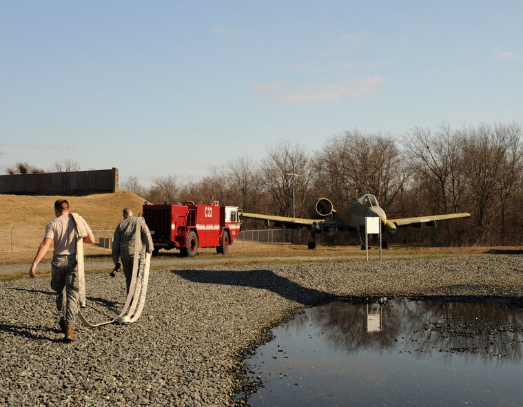 Firefighters from the 2nd Civil Engineer Squadron carry a hose towards a fire truck on Barksdale Air Force Base, La., Jan. 23. The 2 CES firefighters practiced firefighting tactics on a mock A-10 Thunderbolt II. (U.S. Air Force photo/Airman 1st Class Benjamin Gonsier)