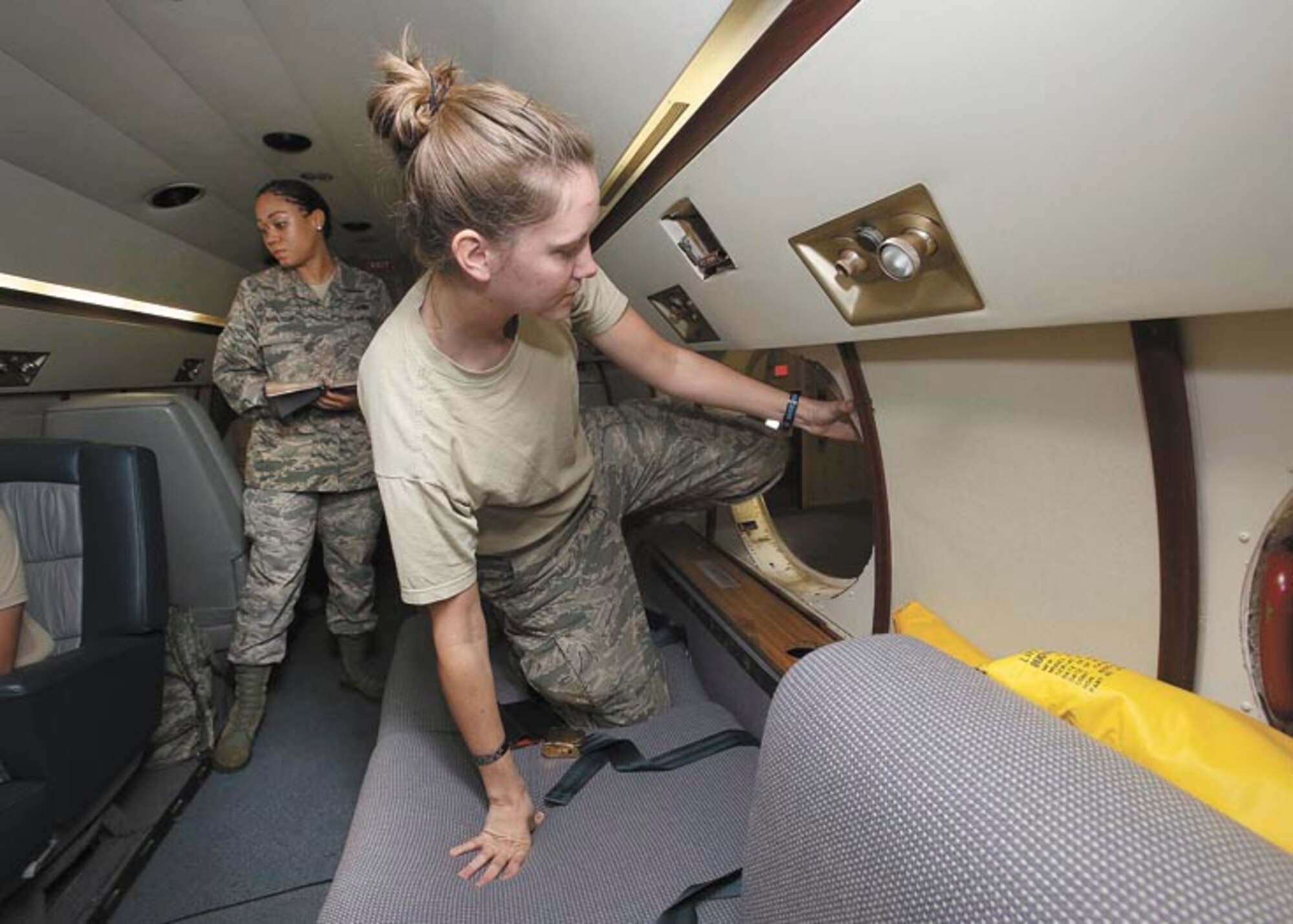 Senior Airman Monique Nelson practices emergency evacuation procedures from the trainer aircraft during a water evacuation while Senior Airman Jaqueline Shelton observes.  (Photo by Robbin Cresswell)