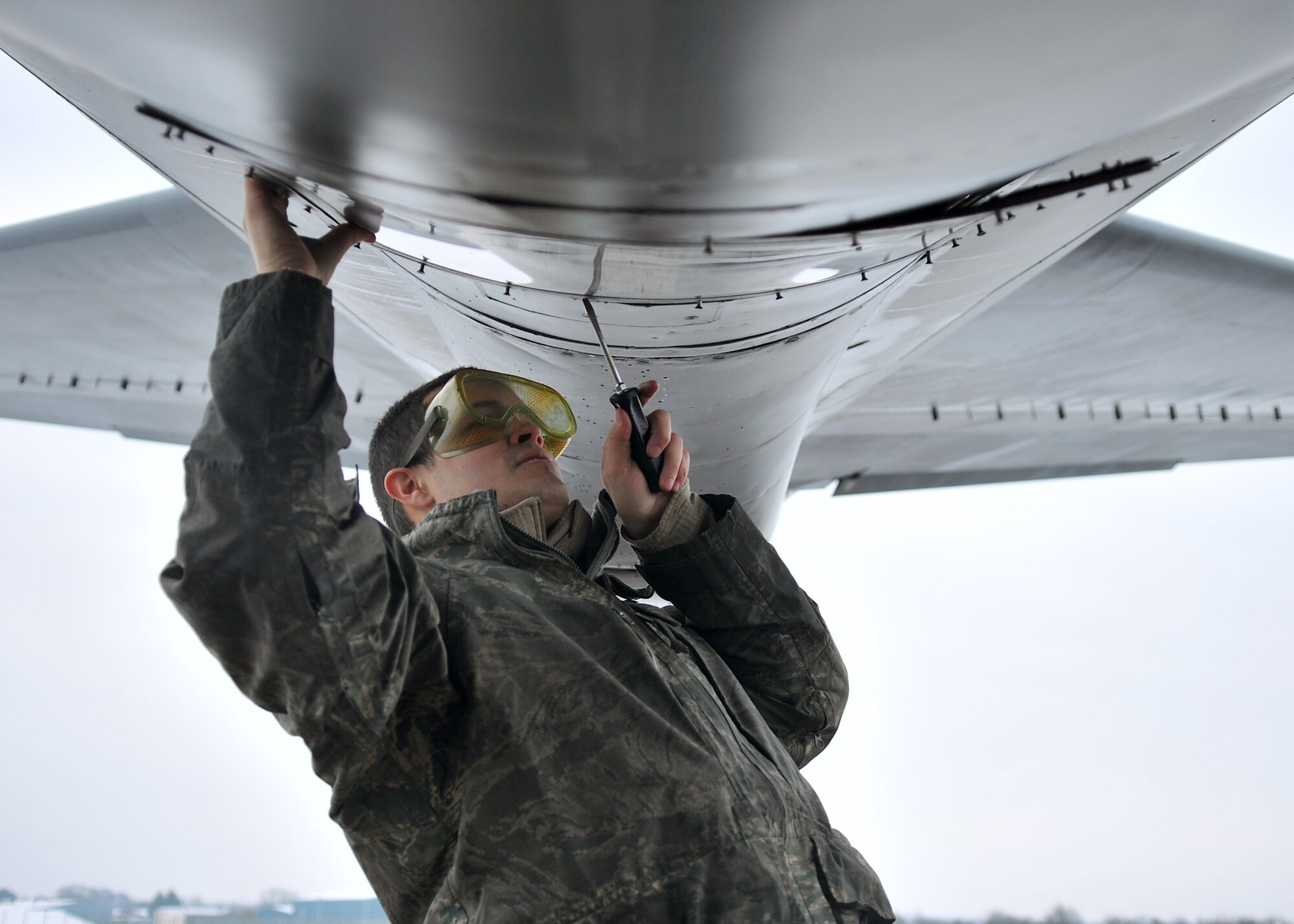 Senior Airman Spencer Lujan, 100th Aircraft Maintenance Squadron crew chief from St. Peters, Mo., unscrews a KC-135 Stratotanker boom sighting door on the flightline Jan. 23, 2013, at RAF Mildenhall, England. Crew chiefs and other maintenance personnel work together to ensure aircraft are safe and ready prior to each mission. (U.S. Air Force photo by Senior Airman Jerilyn Quintanilla/Released)  
