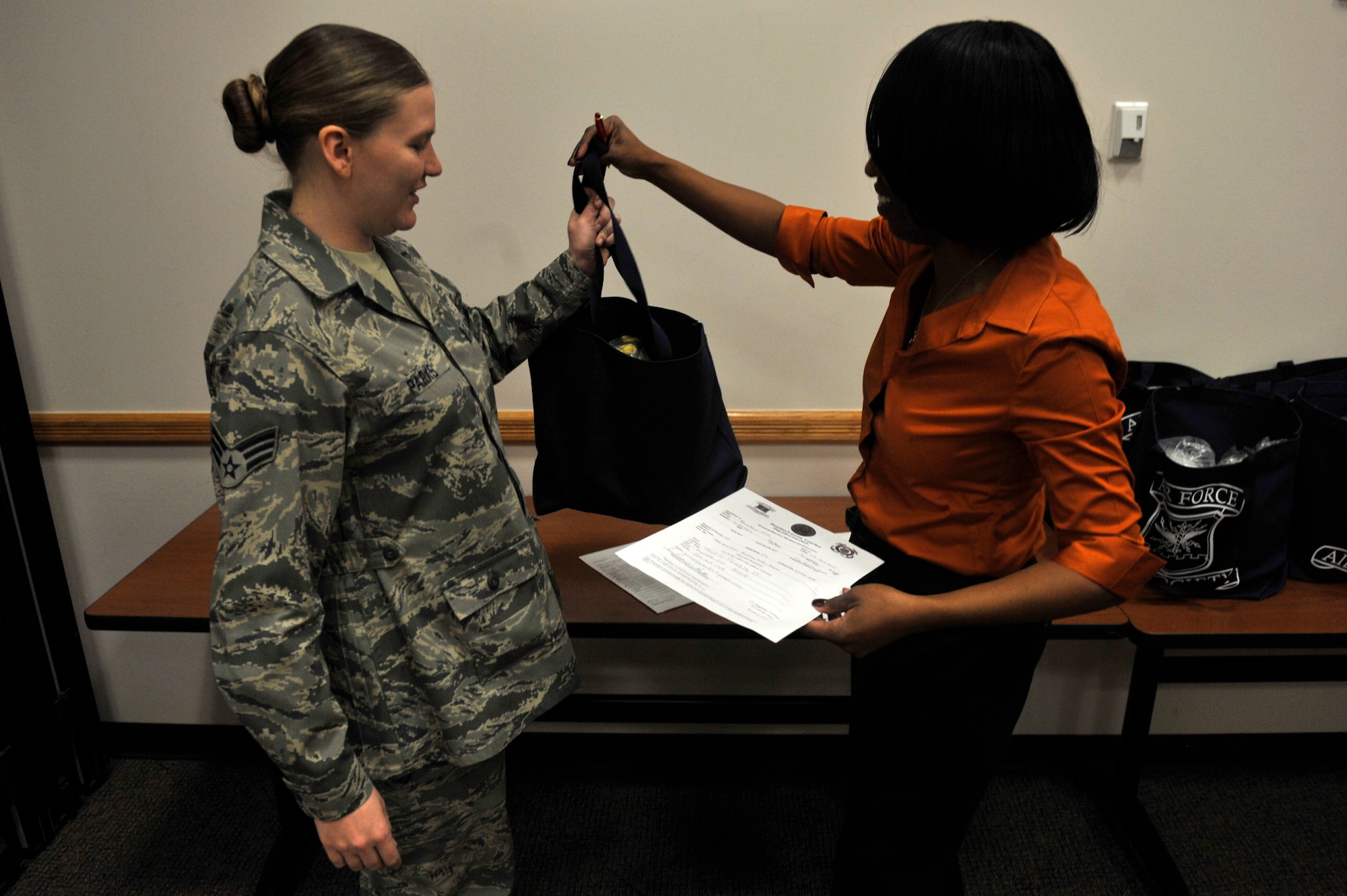 Senior Airman Julieann Parks, 460th Space Communications Squadron, left, receives a bundle from Latoya Marble, Airman and Family Readiness Center community readiness consultant, after the Bundles for Babies seminar Jan. 23, 2013, at Buckley Air Force Base, Colo. Every other month the A&FRC provides parents an abundance of information and bundles of baby products to expecting families. (U.S. Air Force photo by Airman 1st Class Riley Johnson/Released)