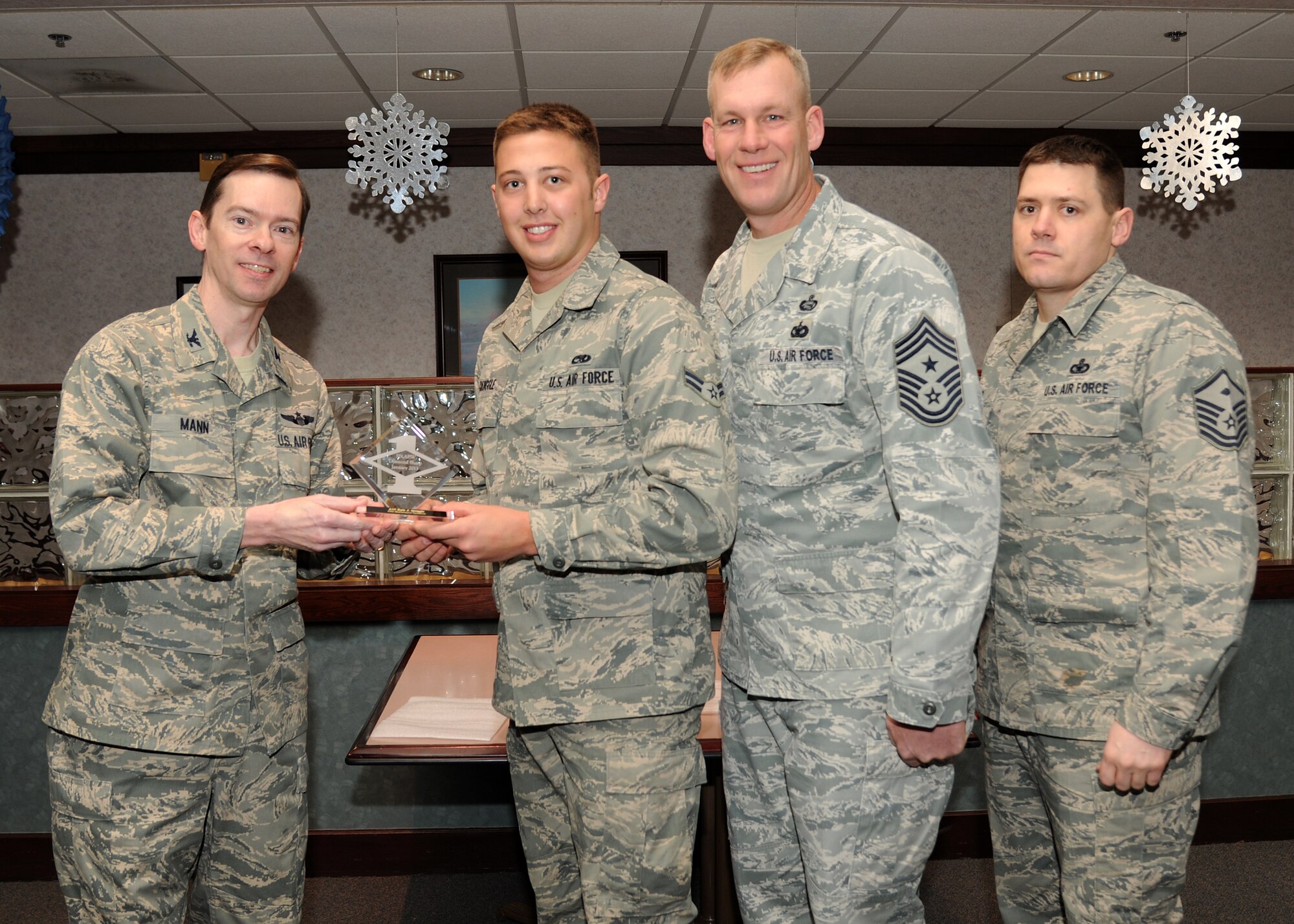 Col. Christopher Mann, 319th Air Base Wing vice commander, presents Airman 1st Class Kyle Quiggle, 69th Maintenance Squadron, with a Diamond Sharp Award Jan. 24, 2013, at Airey Dining Facility on Grand Forks Air Force Base, N. D., accompanied by 319th ABW Command Chief Master Sgt. David Carlson and Master Sgt. Joseph Rind, 69th MXS first sergeant. The Diamond Sharp Award is given to Airmen who epitomize service before self and strive for excellence at work and off duty. (U.S. Air Force photo/Airman 1st Class Ashley N. Taylor)  