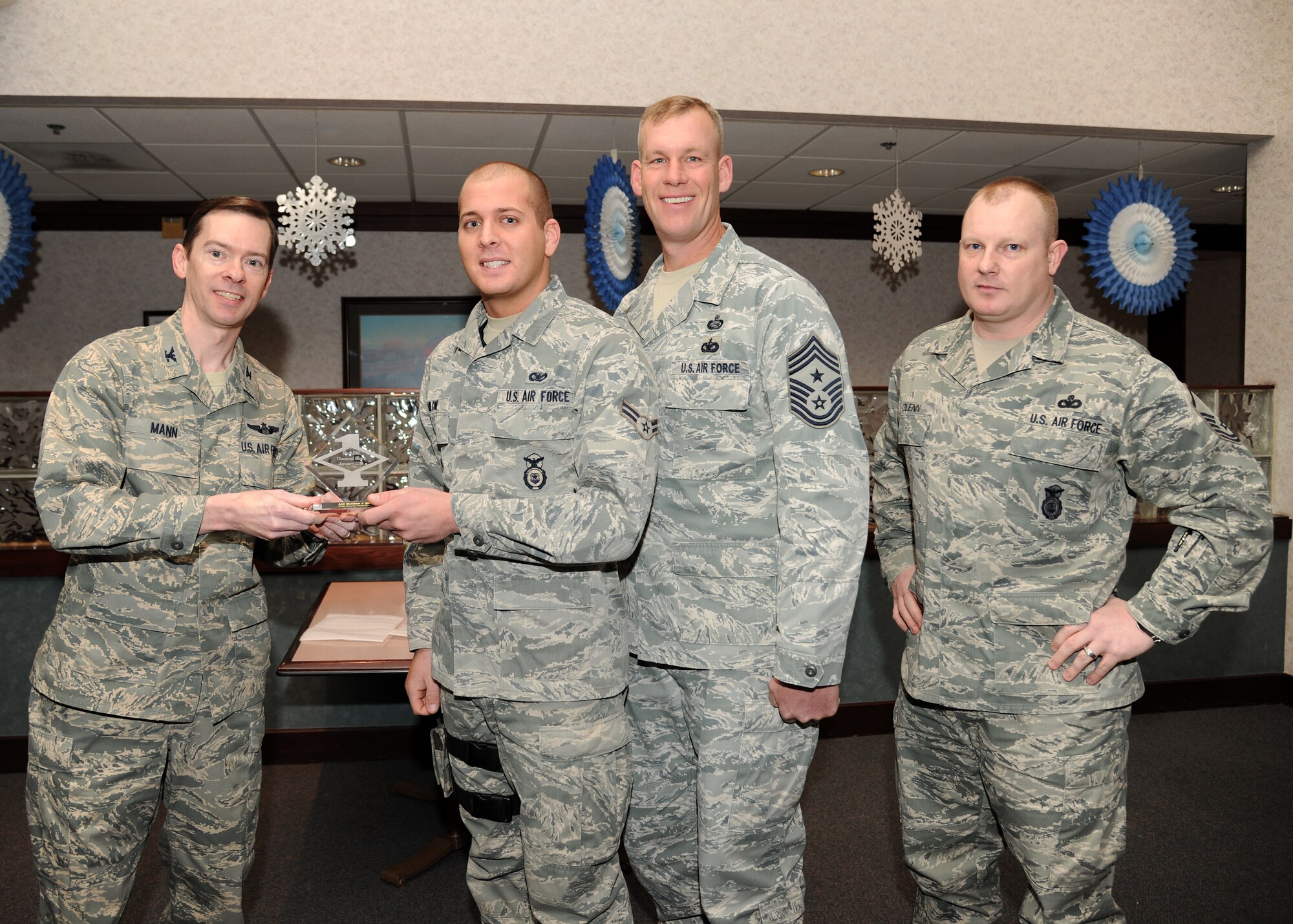 Col. Christopher Mann, 319th Air Base Wing vice commander, presents Airman 1st Class Matthew Milone, 319th Security Forces Squadron, with a Diamond Sharp Award Jan. 24, 2013, at Airey Dining Facility on Grand Forks Air Force Base, N. D., accompanied by 319th ABW Command Chief Master Sgt. David Carlson and Master Sgt. Michael Glenn, 319th SFS operations superintendent. The Diamond Sharp Award is given to Airmen who epitomize service before self and strive for excellence at work and off duty. (U.S. Air Force photo/Airman 1st Class Ashley N. Taylor)  
