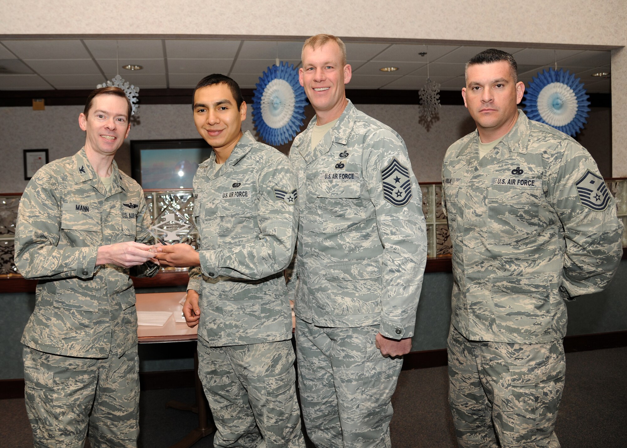 Col. Christopher Mann, 319th Air Base Wing vice commander, presents Senior Airman Marco Nava, 319th Force Support Squadron, with a Diamond Sharp Award Jan. 24, 2013, at Airey Dining Facility on Grand Forks Air Force Base, N. D., accompanied by 319th ABW Command Chief Master Sgt. David Carlson and Master Sgt. Luis Vela, 319th FSS first sergeant.  The Diamond Sharp Award is given to Airmen who epitomize service before self and strive for excellence at work and off duty. (U.S. Air Force photo/Airman 1st Class Ashley N. Taylor)
