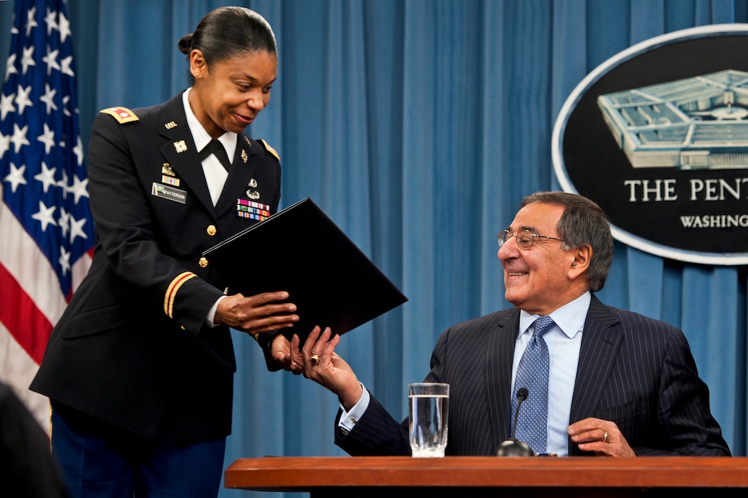 Defense Secretary Leon E. Panetta hands Army Lt. Col. Tamatha Patterson a document he signed during a news conference at the Pentagon, Jan. 24, 2013, to lift the Defense Department's ban on women in direct ground combat roles. DOD photo by Erin A. Kirk-Cuomo