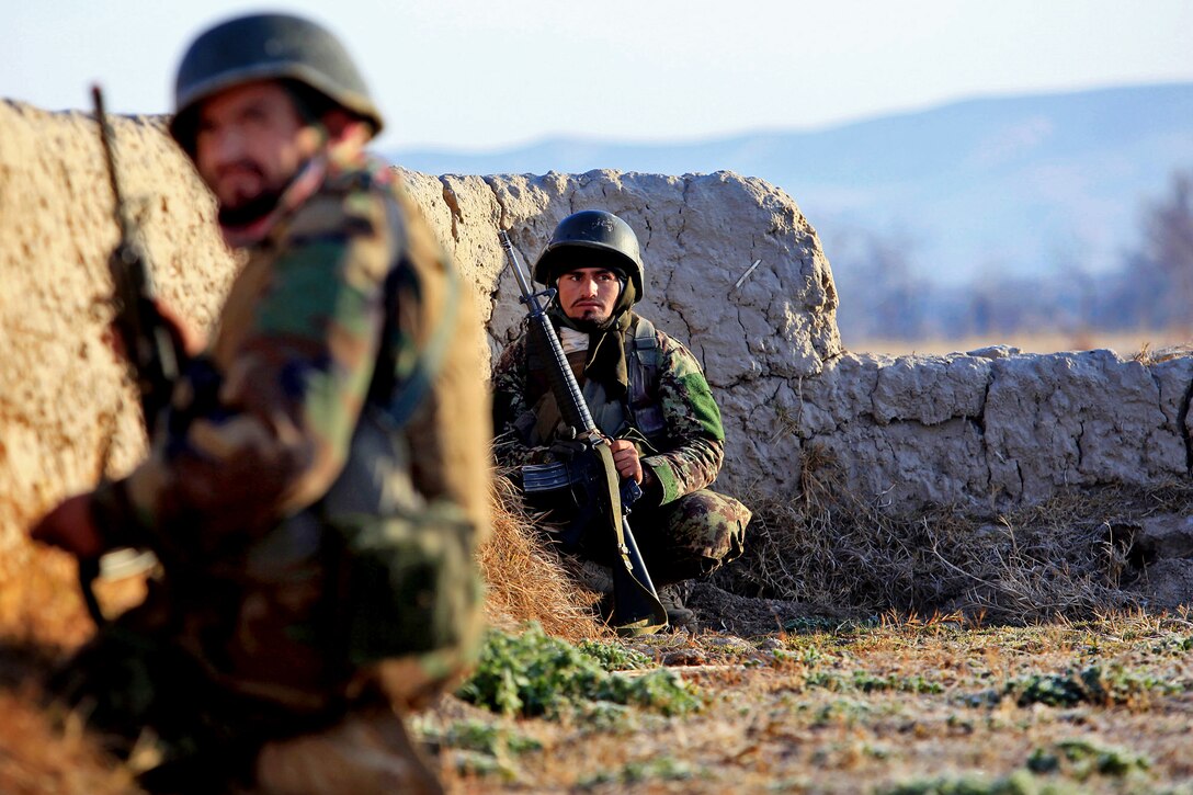 Afghan soldiers take cover behind a wall while receiving enemy fire during Operation New Hope in Kajaki, Afghanistan, Jan. 16, 2013.