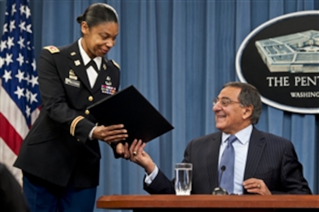 Defense Secretary  Leon E. Panetta hands Army Lt. Col. Tamatha Patterson a document he signed during a press conference at the Pentagon, Jan. 24, 2013, to lift the Defense Department's ban on women in combat roles.