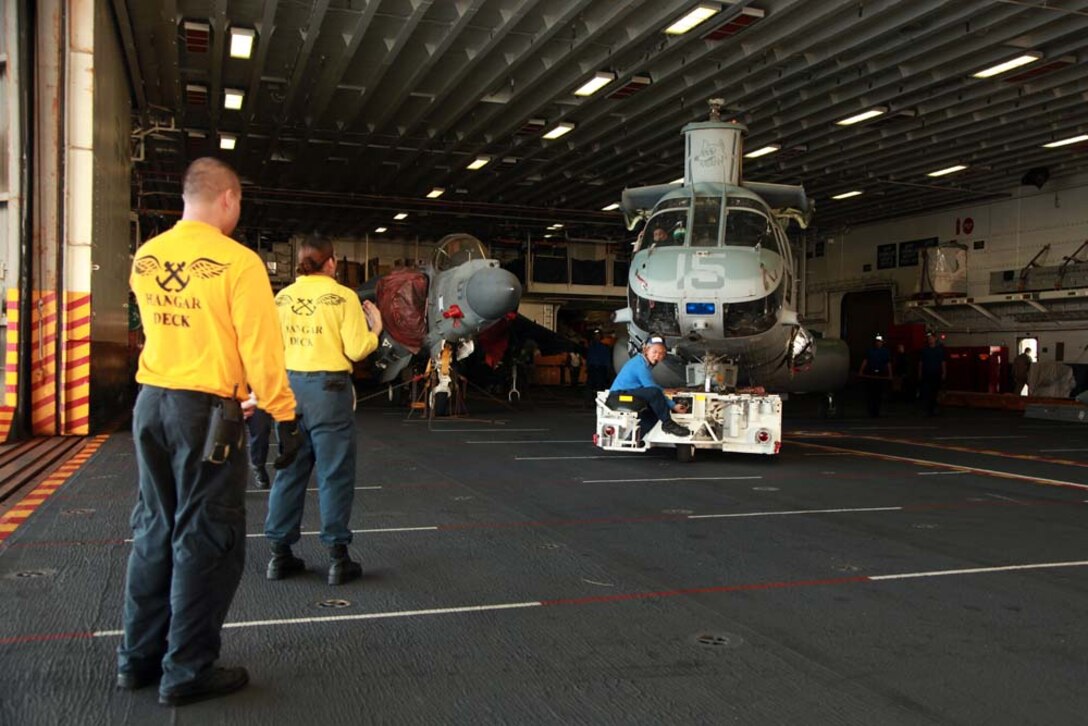 Sailors with Hangar Deck Control, USS Peleliu, move a CH-46E Sea Knight with Marine Medium Helicopter Squadron 364 (Rein.), 15th Marine Expeditionary Unit, in the hangar bay of the USS Peleliu, Jan. 18. The 15th MEU is deployed as part of the Peleliu Amphibious Ready Group as a U.S. Central Command theater reserve force, providing support for maritime security operations and theater security cooperation efforts in the U.S. 5th Fleet area of responsibility. (U.S. Marine Corps photo by Cpl. John Robbart III)