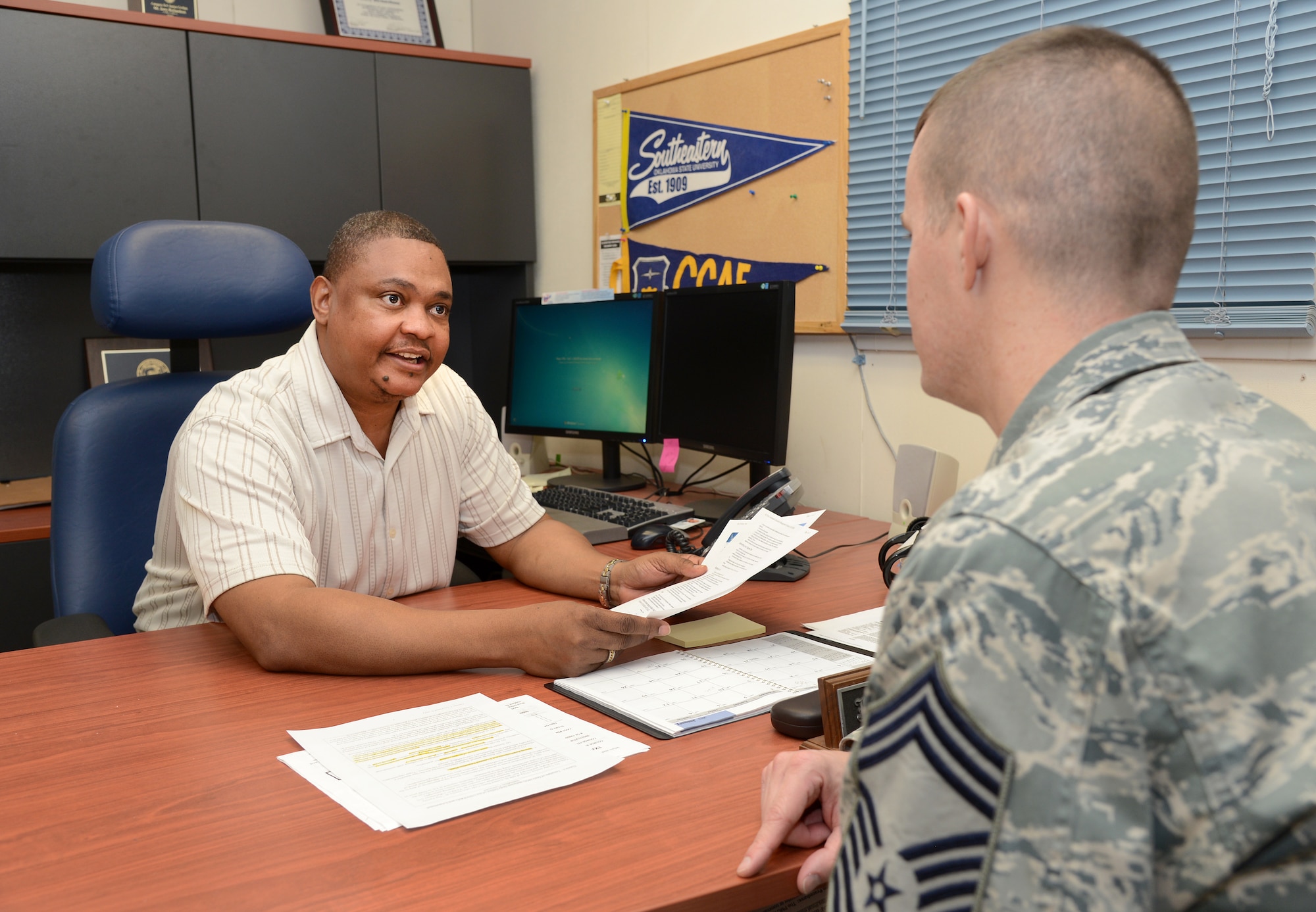 Air Force photo by Kelly White
Jerry Richardson, an education specialist with the 72nd Force Support Squadron, and Chief Master Sgt. Timothy Corbeil, chief enlisted manager of the 3rd Combat Communications Support Squadron, discuss changes in tuition-assistance benefits on Jan. 18 in the Education offices located in Bldg. 201SE. Service members need to ensure they apply for benefits 60 days prior to their class start date and no less than 10 days, or they will run the risk of their TA benefits not being approved. It is also the service members’ responsibility to ensure that their grades are properly posted to the Air Force Portal.