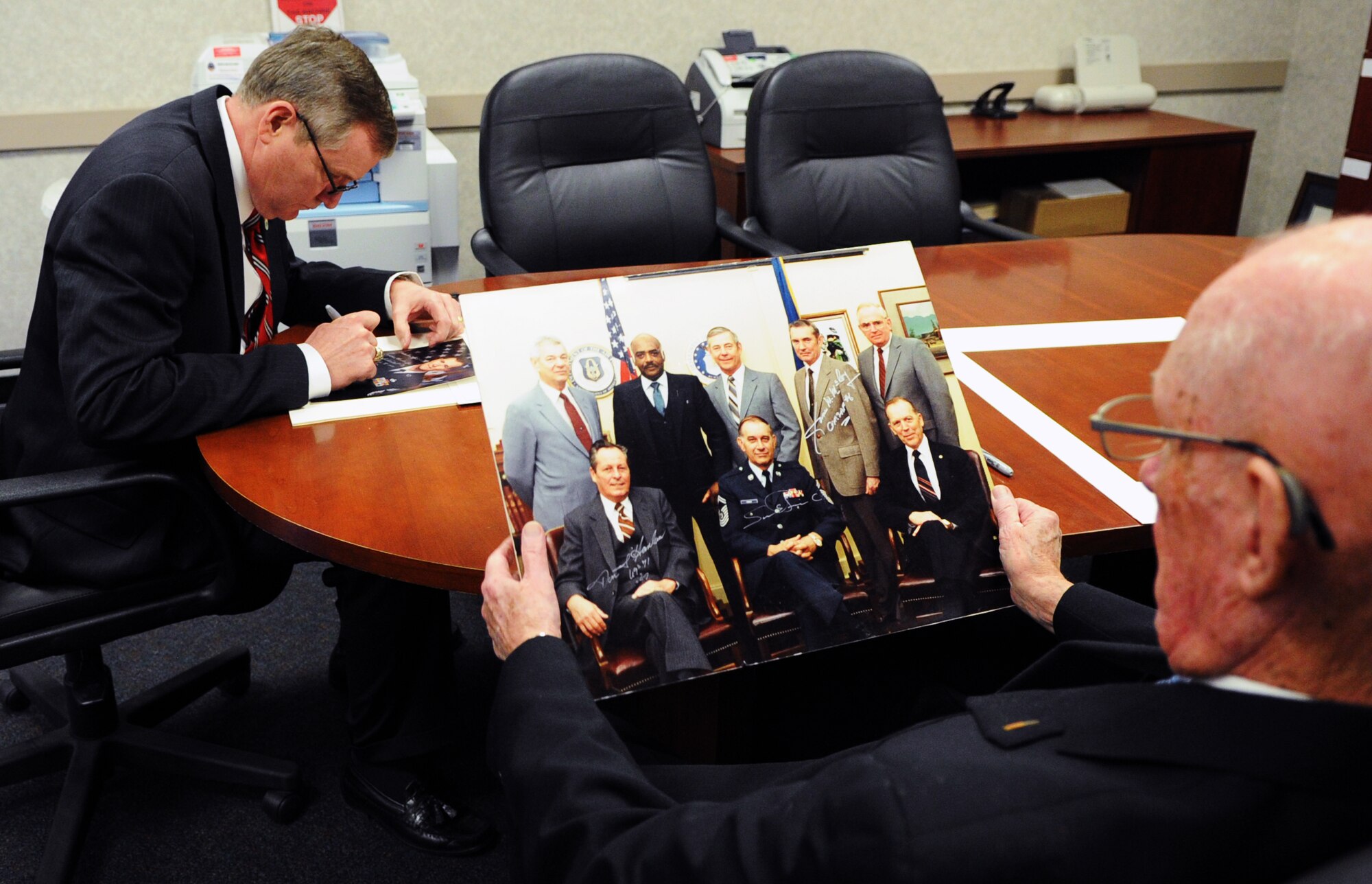 Former Chief Master Sergeants of the Air Force (CMSAF) Eric W. Benken and James M. McCoy sign photos at the CMSAF Donald L. Harlow Airman Leadership School on Joint Base Andrews, Md., Jan. 24, 2013. They were two of six former CMSAF who advised students on leading a team. (U.S. Air Force photo/ Airman 1st Class Nesha Humes)(Released)