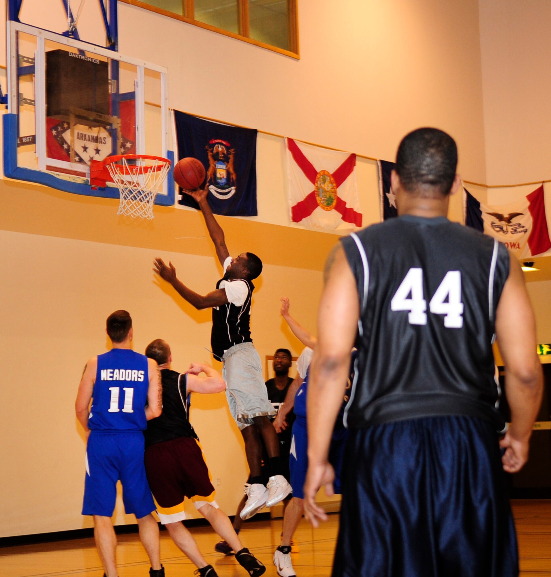 Senior Airman Bryant Draper, center, 100th Aircraft Maintenance Squadron communication and navigation mission systems craftsman, goes in to the paint for a layup during an intramural basketball game between the 100th Maintenance Group and the 100th Maintenance Operations Squadron Jan. 24, 2013, at the Hardstand Fitness Center on RAF Mildenhall, England. The 100th MXG was victorious over the 100th MOS with a final score of 54-28. (U.S. Air Force photo by Airman 1st Class Dillon Johnston/Released)