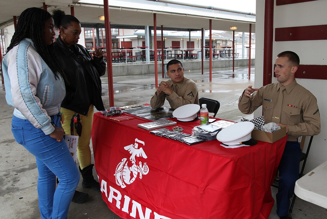 Lance Cpl Gabriel Nava and PFC Braydon Clendenning speak with Yolanda Kersey and her daughter Arionne Bradford about the Marine Corps and what it offers at Kearny High School, San Diego, CA on Jan 26. Bradford was interested in the many aspects of what the Marine Corps could offer and the career choices she could pursue within the Marine Corps as well.