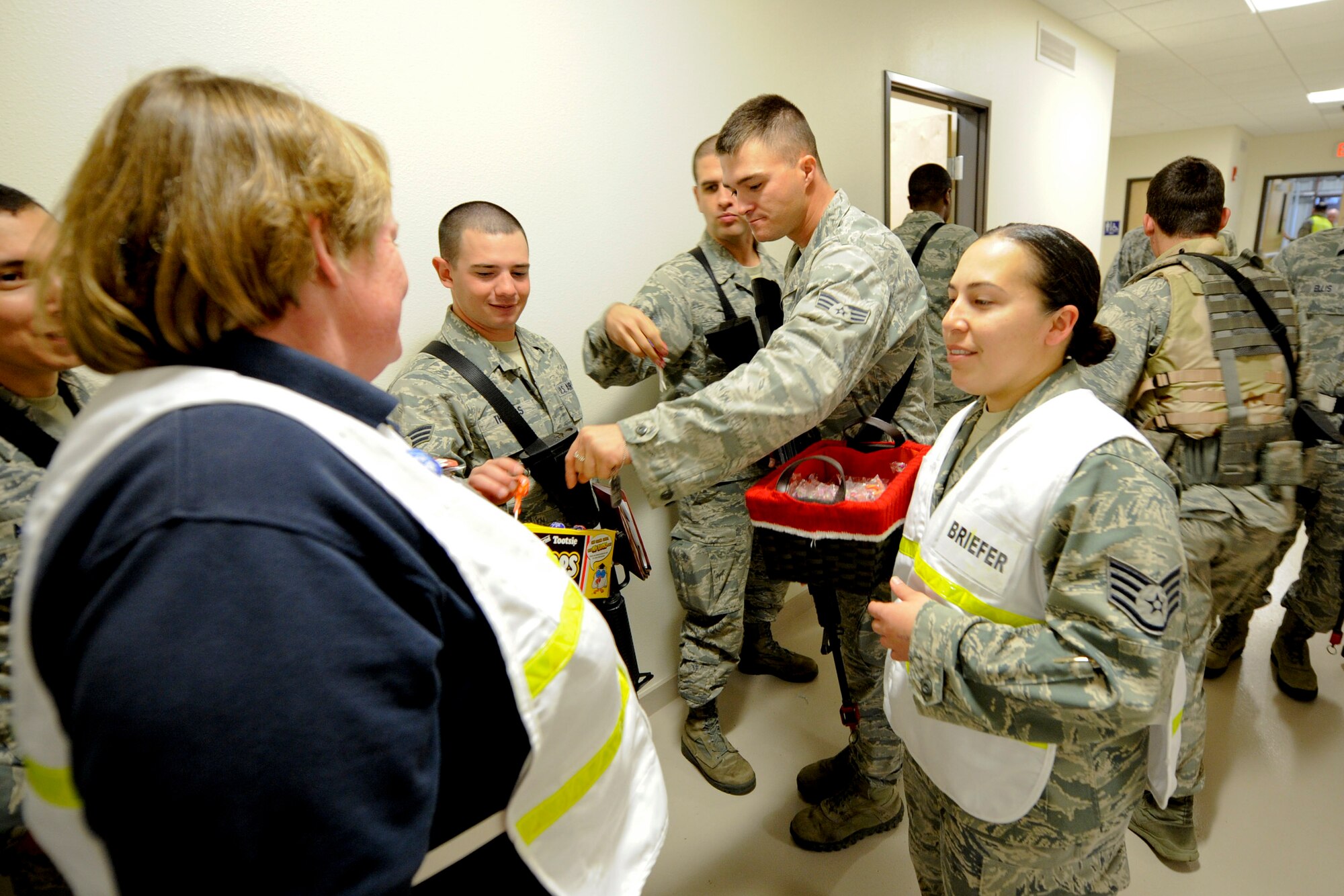 VANDENBERG AIR FORCE BASE, Calif. -- 30th Security Force Squadron members get candy from Donna Rathbun, the 30th Space Wing sexual assault response coordinator, and Staff Sgt. Elisa Panek, a 30th Space Wing chaplains assistant, while processing through the Personnel Deployment Function line during an exercise here Friday, Jan. 25, 2013. The PDF line was held as part of a Consolidated Unit Inspection, a biannual inspection used to measure the base's discipline, readiness and war fighting capability through exercises, inspection and evaluations. (U.S. Air Force photo/Staff Sgt. Levi Riendeau)
