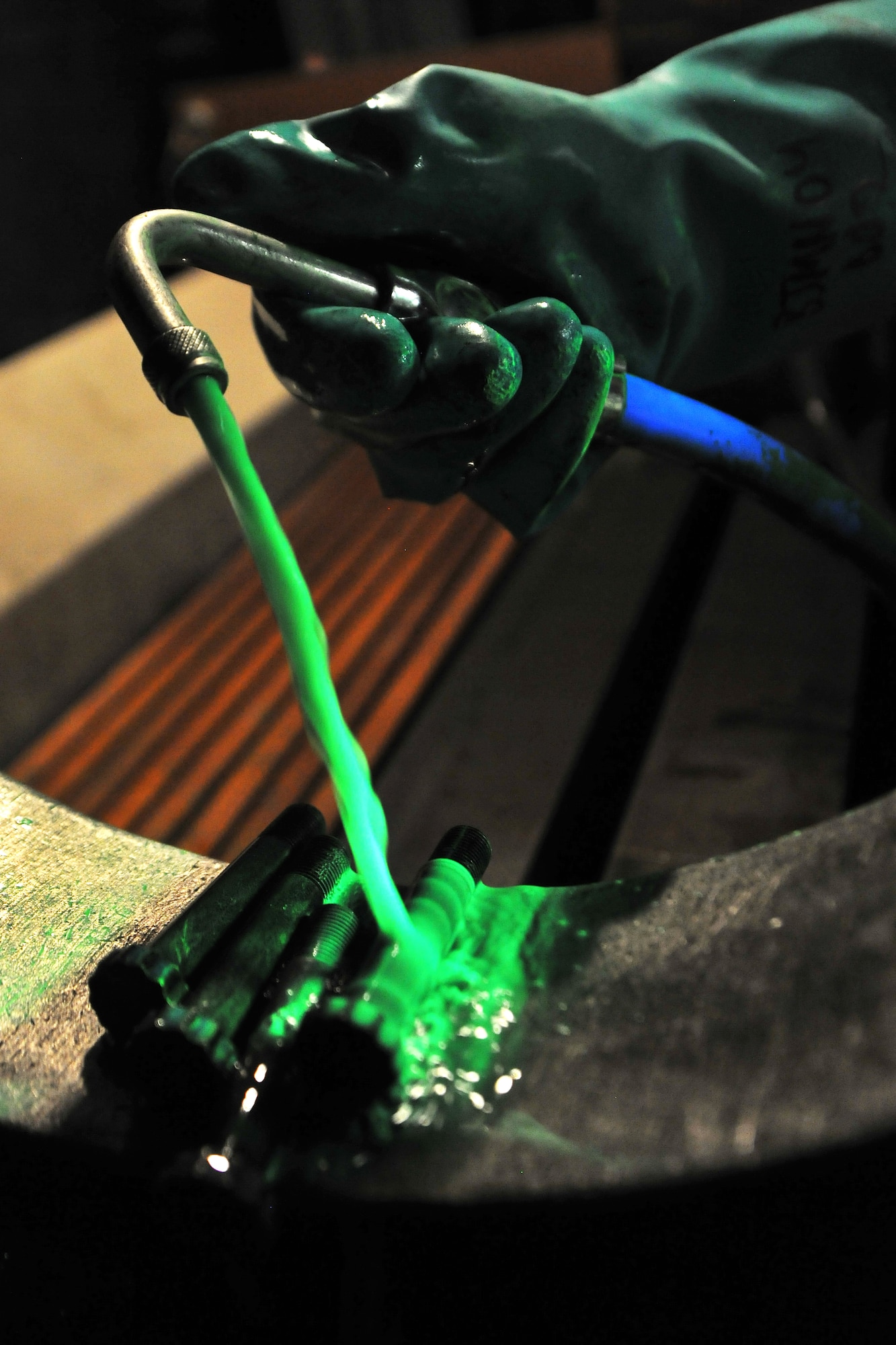 Senior Airman Hugo Garcia, 455th Expeditionary Maintenance Squadron Non-Destructive Inspection lab Journeyman, pours magnetic particles over an A-10 wheel bolt at Bagram Airfield, Afghanistan, Jan. 21, 2013.  A magnetic particle solution is used to fill any cracks in a suspected damaged piece of equipment which will then glow under a black light to determine whether it is damaged.  (U.S. Air Force photo/Senior Airman Chris Willis)
