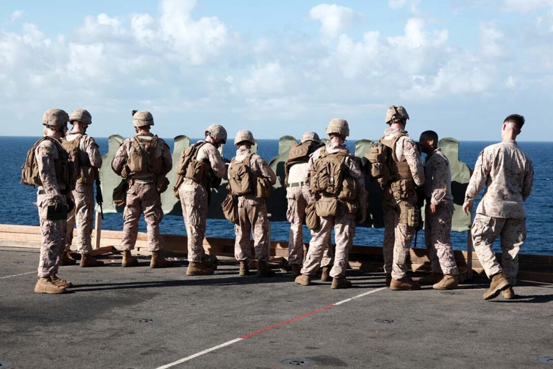 Marines with Kilo Company, Battalion Landing Team 3/5, 15th Marine Expeditionary Unit, review their targets after firing on the flight deck of the USS Peleliu, Jan. 22. Kilo Company is one of three rifle companies in BLT 3/5, the 15th MEU's ground combat element. The 15th MEU is deployed as part of the Peleliu Amphibious Ready Group as a U.S. Central Command theater reserve force, providing support for maritime security operations and theater security cooperation efforts in the U.S. 5th Fleet area of responsibility. (U.S. Marine Corps photo by Cpl. John Robbart III)