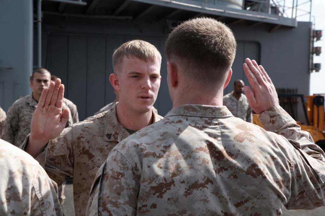 Corporal Daniel R. Boze, assaultman, Weapons Platoon, Kilo Company, Battalion Landing Team 3/5, 15th Marine Expeditionary Unit, re-enlists under the authority of 1st Lt. James P. Rooney, his platoon commander, on the flight deck of the USS Peleliu, Jan. 24. The 15th MEU is deployed as part of the Peleliu Amphibious Ready Group as a U.S. Central Command theater reserve force, providing support for maritime security operations and theater security cooperation efforts in the U.S. 5th Fleet area of responsibility. Boze, 21, is from Queen City, Texas, and Rooney, 25, is from Long Island, N.Y. (U.S. Marine Corps photo by Cpl. John Robbart III)