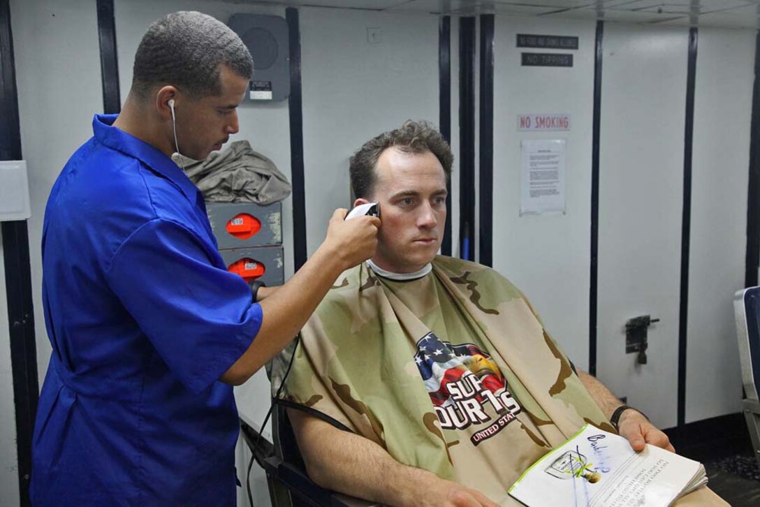 Sergeant Jordan Kelly, chief, Fire Control Team 32, Air Naval Gunfire Liaison Company, Command Element, 15th Marine Expeditionary Unit, gives a haircut to his team leader, Capt. Collin Hannigan, FCT 32 team leader, aboard the USS Rushmore, Jan. 22. The 15th MEU is deployed as part of the Peleliu Amphibious Ready Group as a U.S. Central Command theater reserve force, providing support for maritime security operations and theater security cooperation efforts in the U.S. 5th Fleet area of responsibility. Kelly, 25, is from Mexico, Mo., and Hannigan, 30, Fairfax, Va. (U.S. Marine Corps photo by Cpl. Timothy R. Childers)