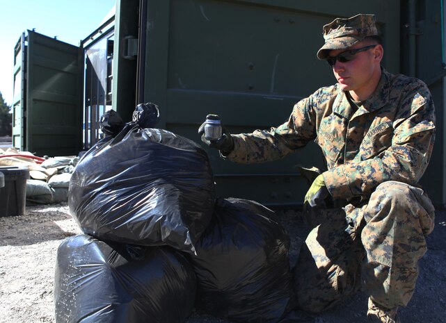 Pvt. Dylan Bolt, a mortarman with 3rd Battalion, 3rd Marine Regiment, 3rd Marine Division, shows off the waste disposal capability of MAGS (Micro Auto Gasification System) here Jan 25. Through the gasification process, a 30-gallon bag of solid waste can be reduced to a jar of baby food. Additionally, the gas produced is captured and used as fuel to sustain the process. MAGS is capable of handling the daily waste disposal needs of approximately 1,000 troops. Bolt, 21, is from Prosser, Wash.