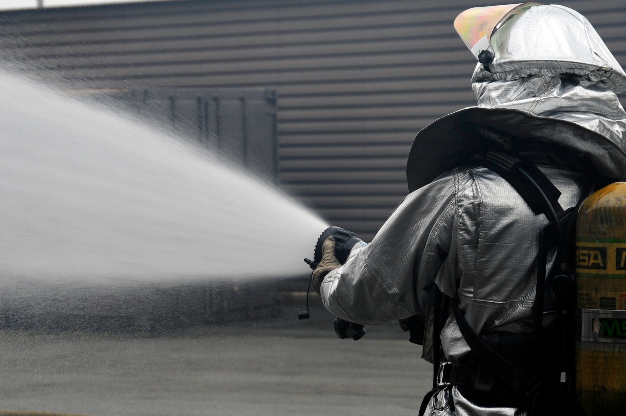 Senior Airman Juan Duarte, 51st Civil Engineer Squadron fire services hand lineman, tests the hose stream before making entry to a smoky building while responding to a fire emergency exercise at Osan Air Base, Republic of Korea, Jan. 24, 2012. Throughout the exercise, the team demonstrated their ability to respond to a trash fire emergency. (U.S. Air Force photo/Airman 1st Class Alexis Siekert) 