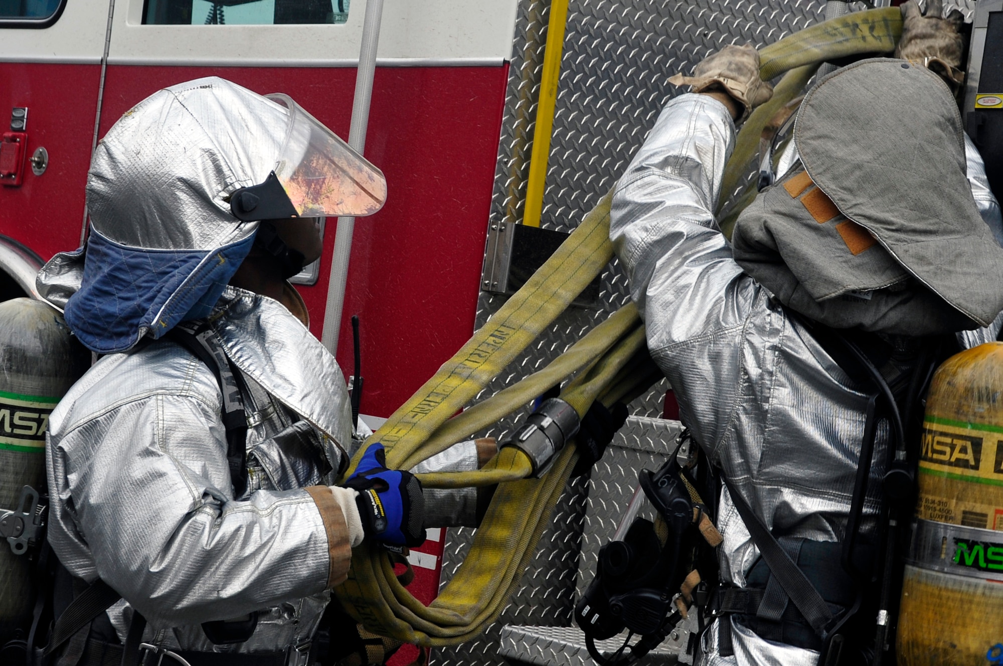 Staff Sgt. Terrell Thomas, left, and Staff Sgt. Travis Barrett, 51st Civil Engineer Squadron fire services lead firefighters, pull down a hose from a truck during a fire exercise at Osan Air Base, Republic of Korea, Jan. 24, 2012. The team demonstrated their ability to respond to a trash fire emergency on the installation. (U.S. Air Force photo/Airman 1st Class Alexis Siekert) 